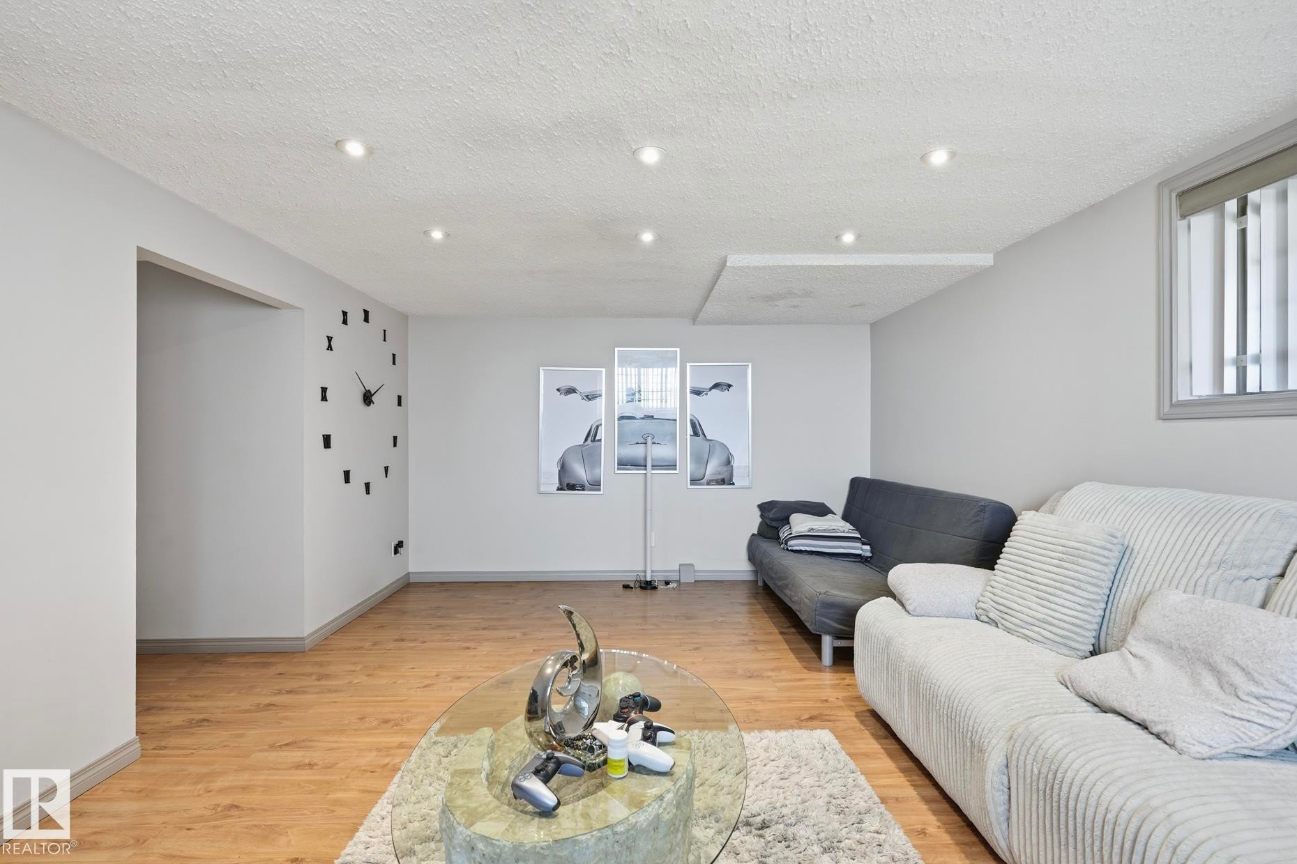 Spacious room featuring wood-finish flooring, recessed lighting, and a white textured ceiling - 12131 101 Street Nw, Edmonton, AB