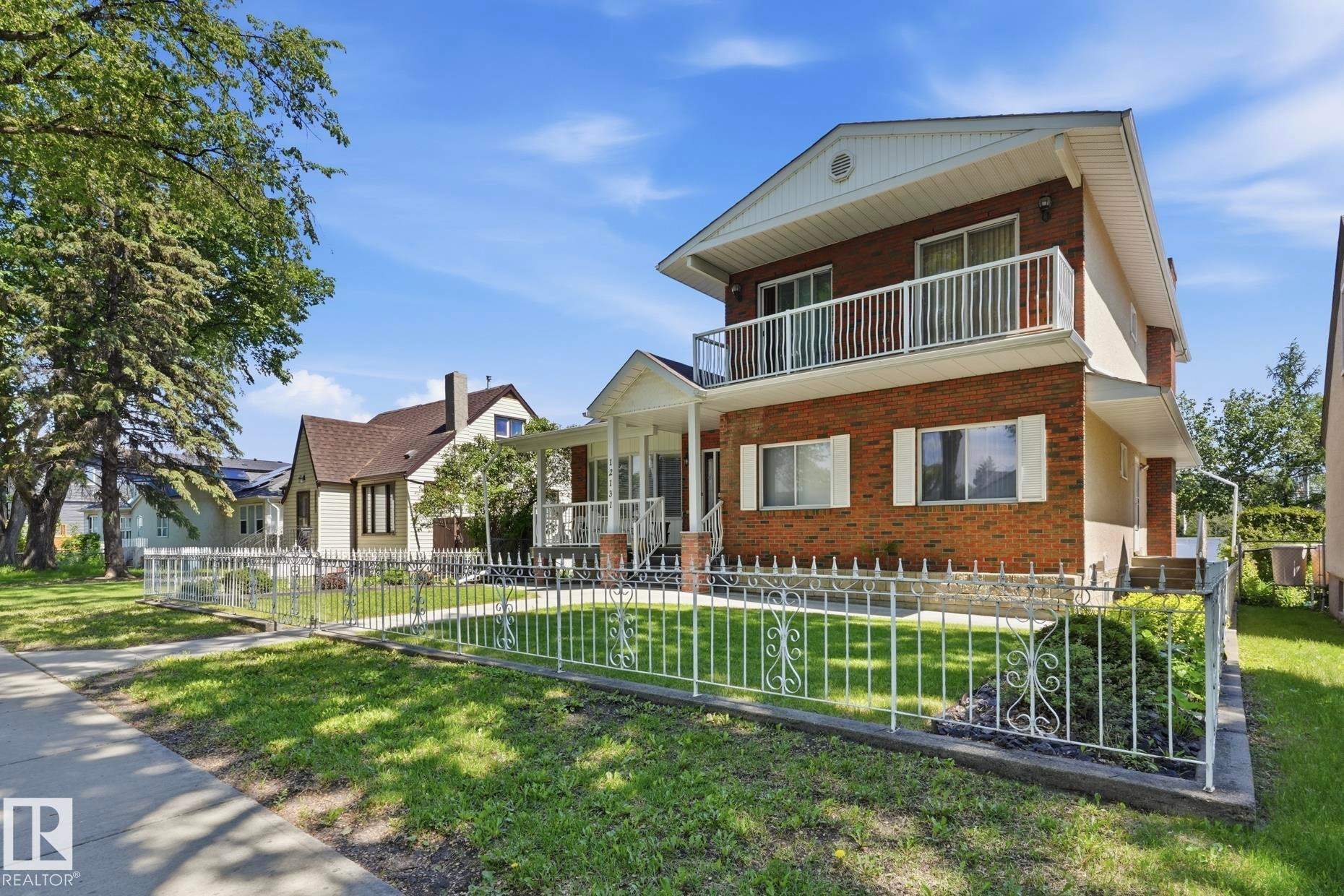 Brick exterior with white accents and a second-story balcony featuring white railings - 12131 101 Street Nw, Edmonton, AB