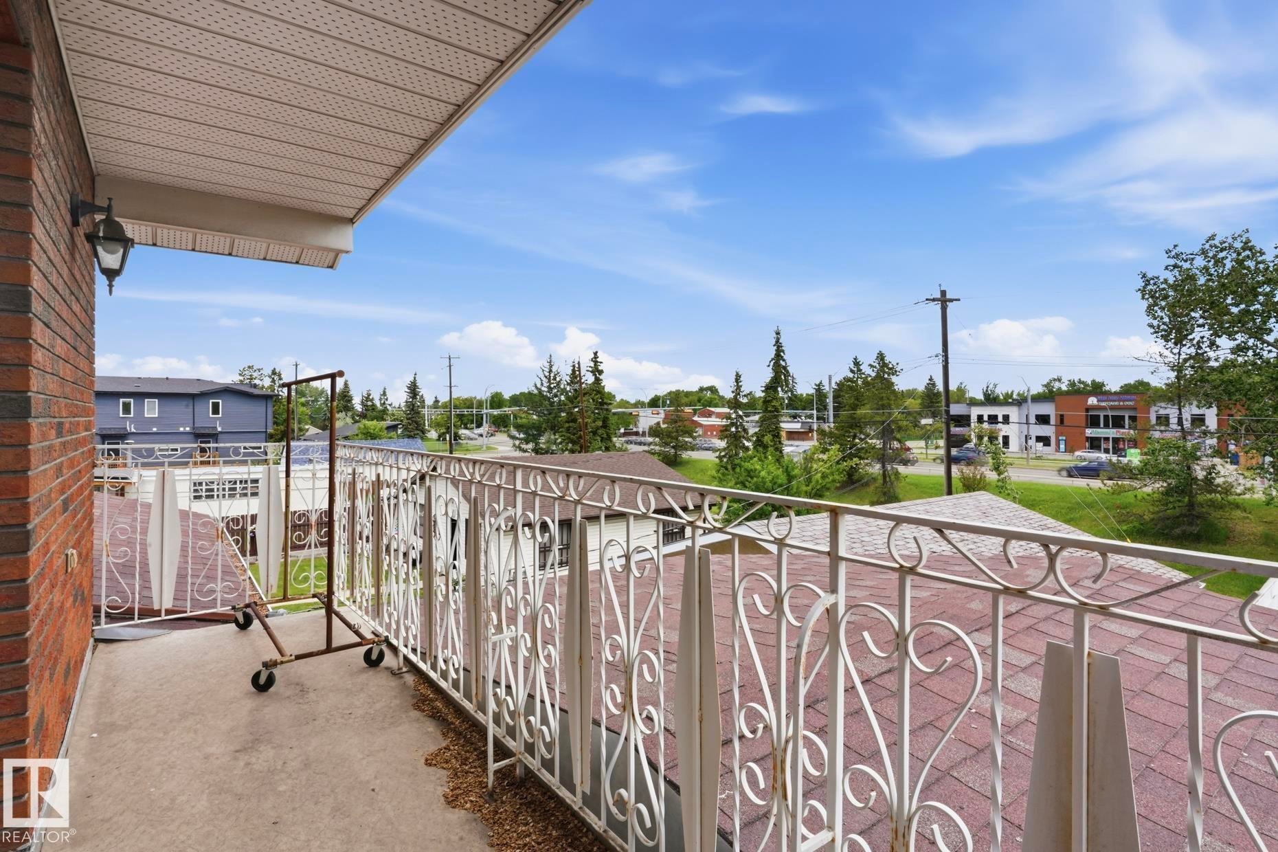 Balcony featuring ornate white metal railings, a concrete surface, and an exterior wall light fixture - 12131 101 Street Nw, Edmonton, AB