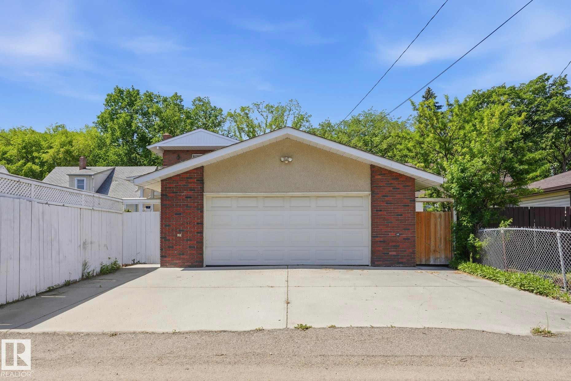 Two-car garage with a white overhead door, brick and stucco exterior, and concrete driveway - 12131 101 Street Nw, Edmonton, AB