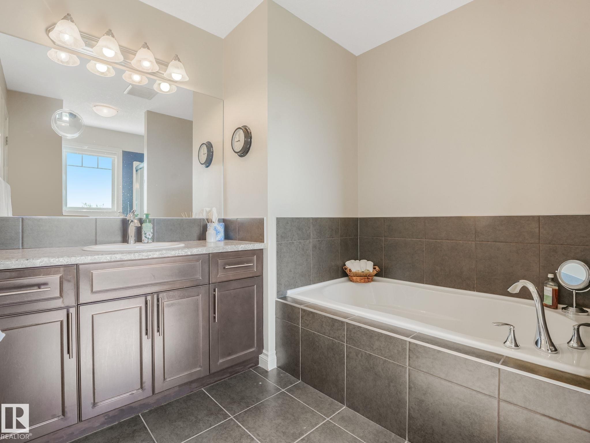 Soaking tub with chrome fixtures, surrounded by dark gray tile - 3 1641 James Mowatt Trail, Edmonton, AB