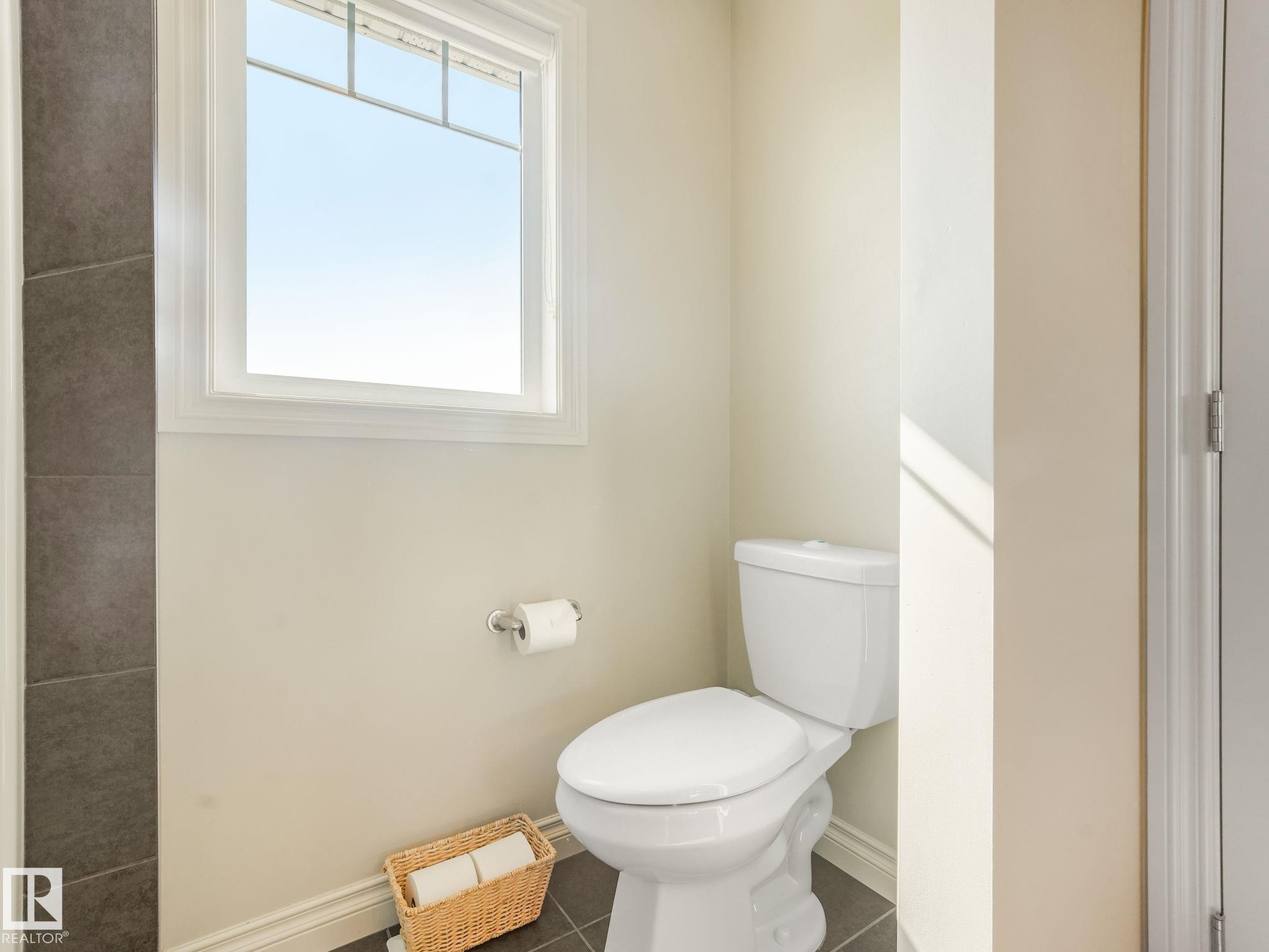 White toilet with a round bowl and tank, set against a light beige wall - 3 1641 James Mowatt Trail, Edmonton, AB