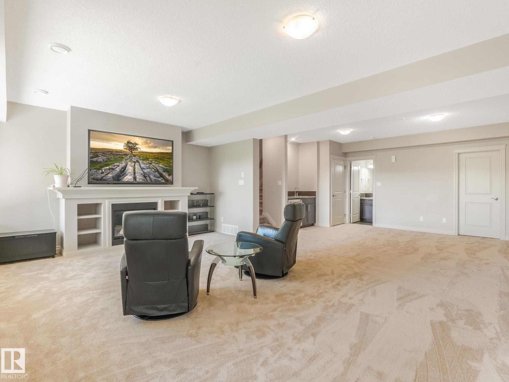 Spacious recreation room featuring light-toned carpeting and recessed lighting - 3 1641 James Mowatt Trail, Edmonton, AB