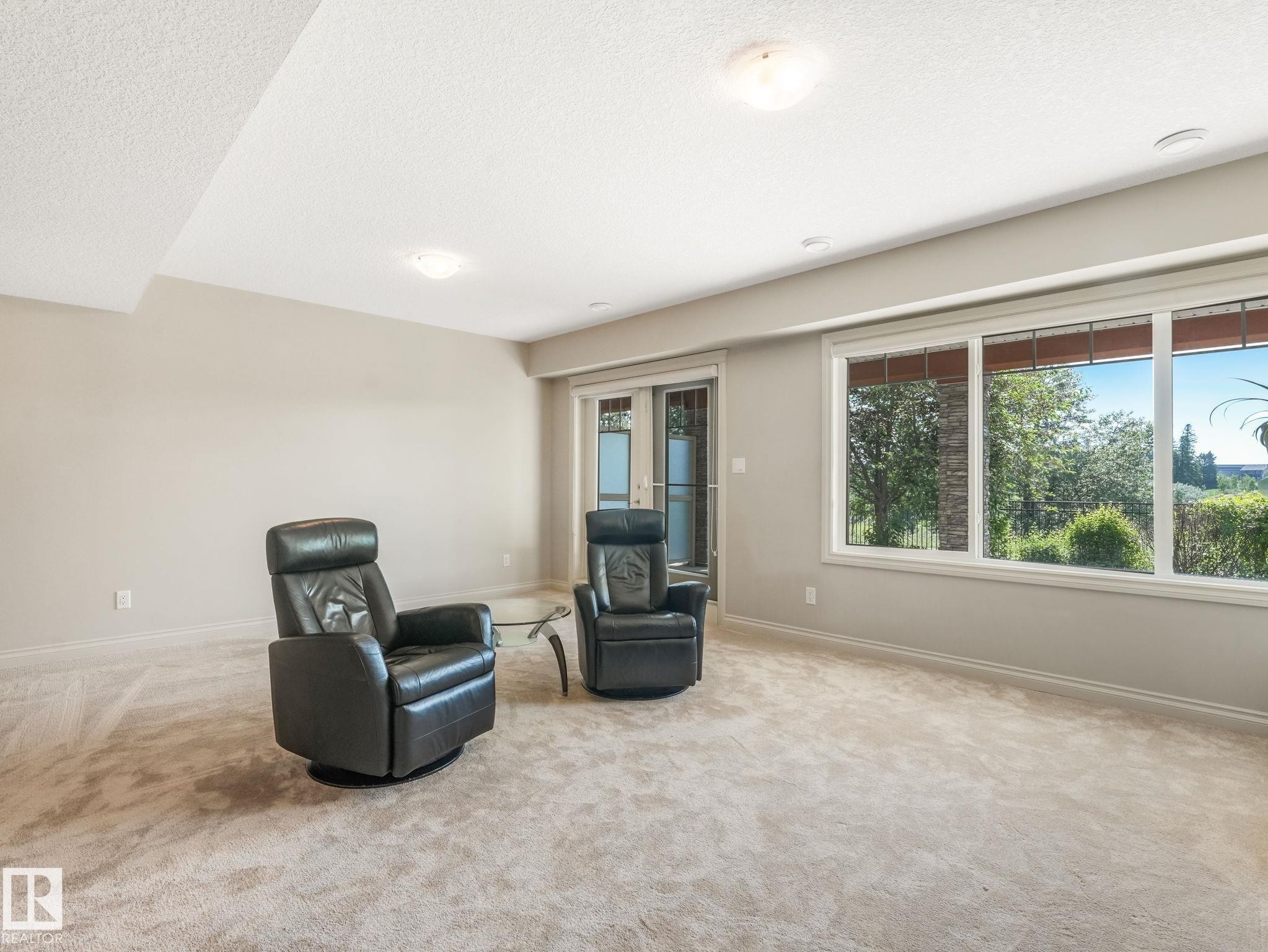 Spacious room featuring multiple large windows and glass French doors, providing abundant natural light - 3 1641 James Mowatt Trail, Edmonton, AB