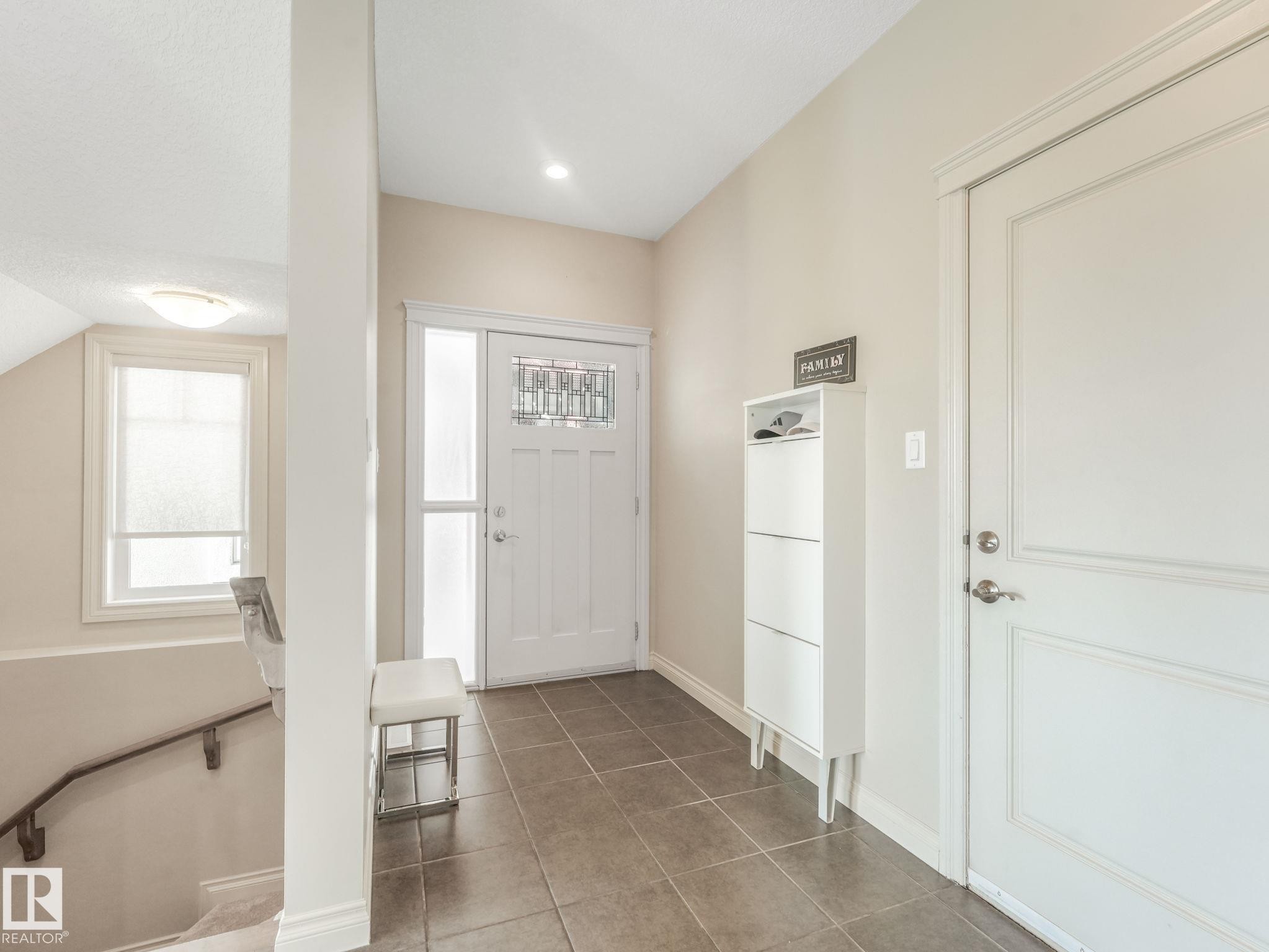 Front entryway with tiled flooring, white paneled door, and a decorative glass insert - 3 1641 James Mowatt Trail, Edmonton, AB
