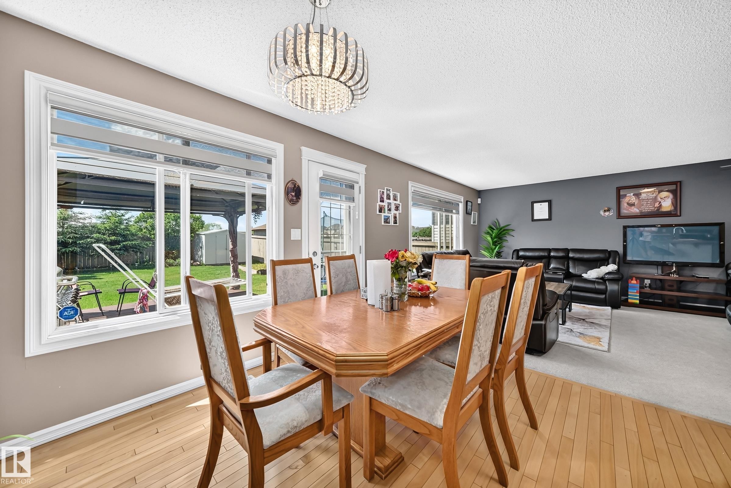 Dining area featuring a contemporary chandelier, light wood-finish flooring, and direct access to the backyard - 3224 26 Street, Edmonton, AB