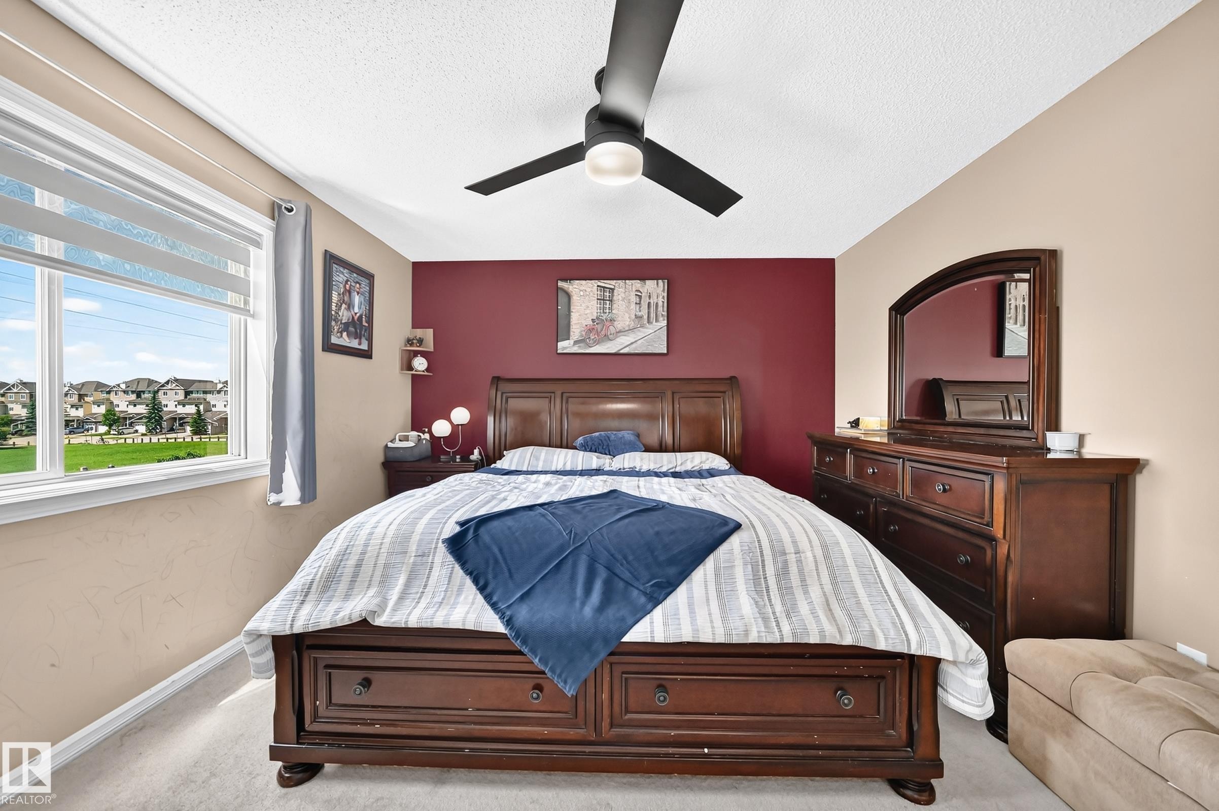 Spacious bedroom featuring neutral wall tones with an accent wall, a large window with roller shades, recessed lighting, and a ceiling fan - 3224 26 Street, Edmonton, AB