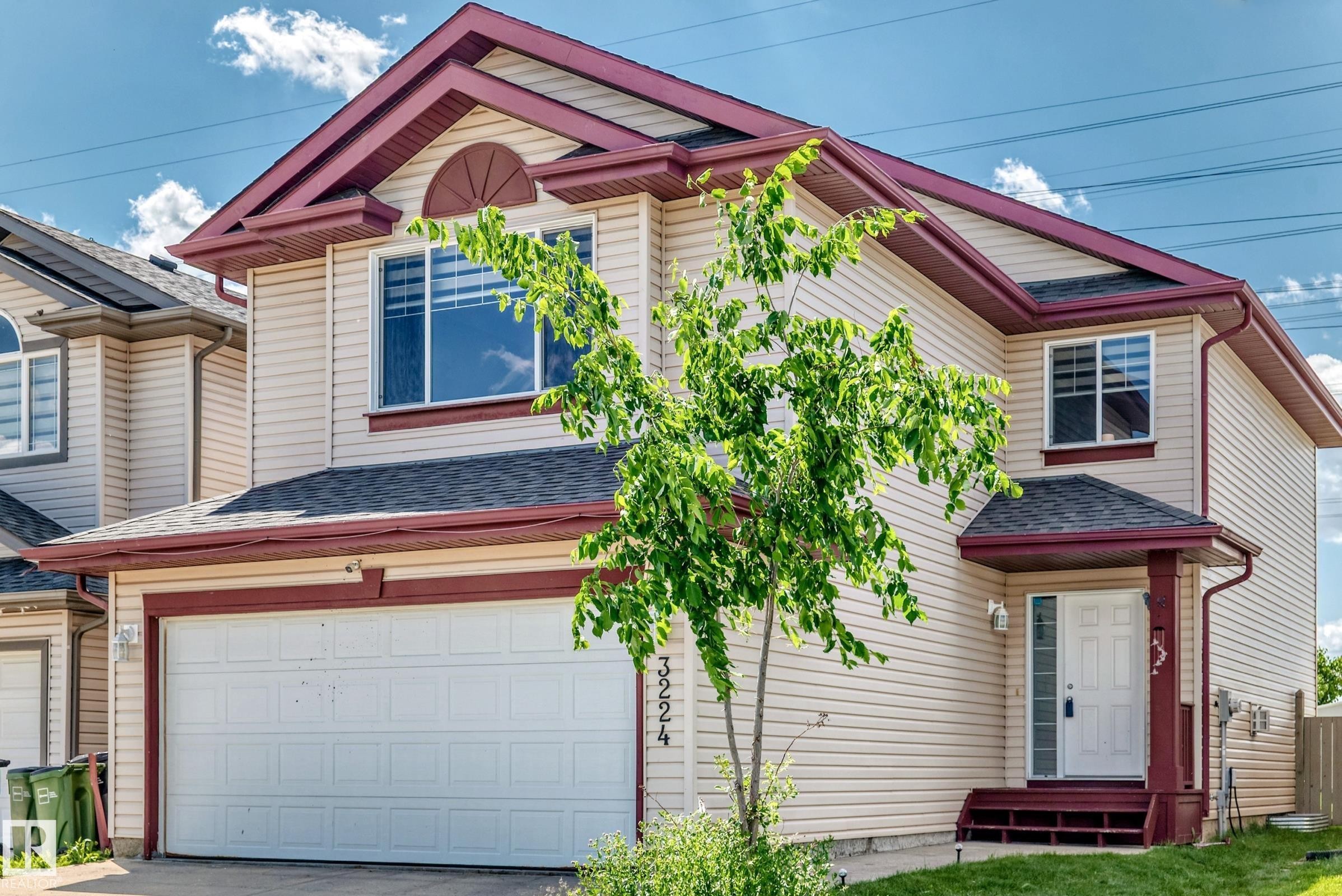 Two-story residence featuring light-toned siding and a burgundy trim accent - 3224 26 Street, Edmonton, AB