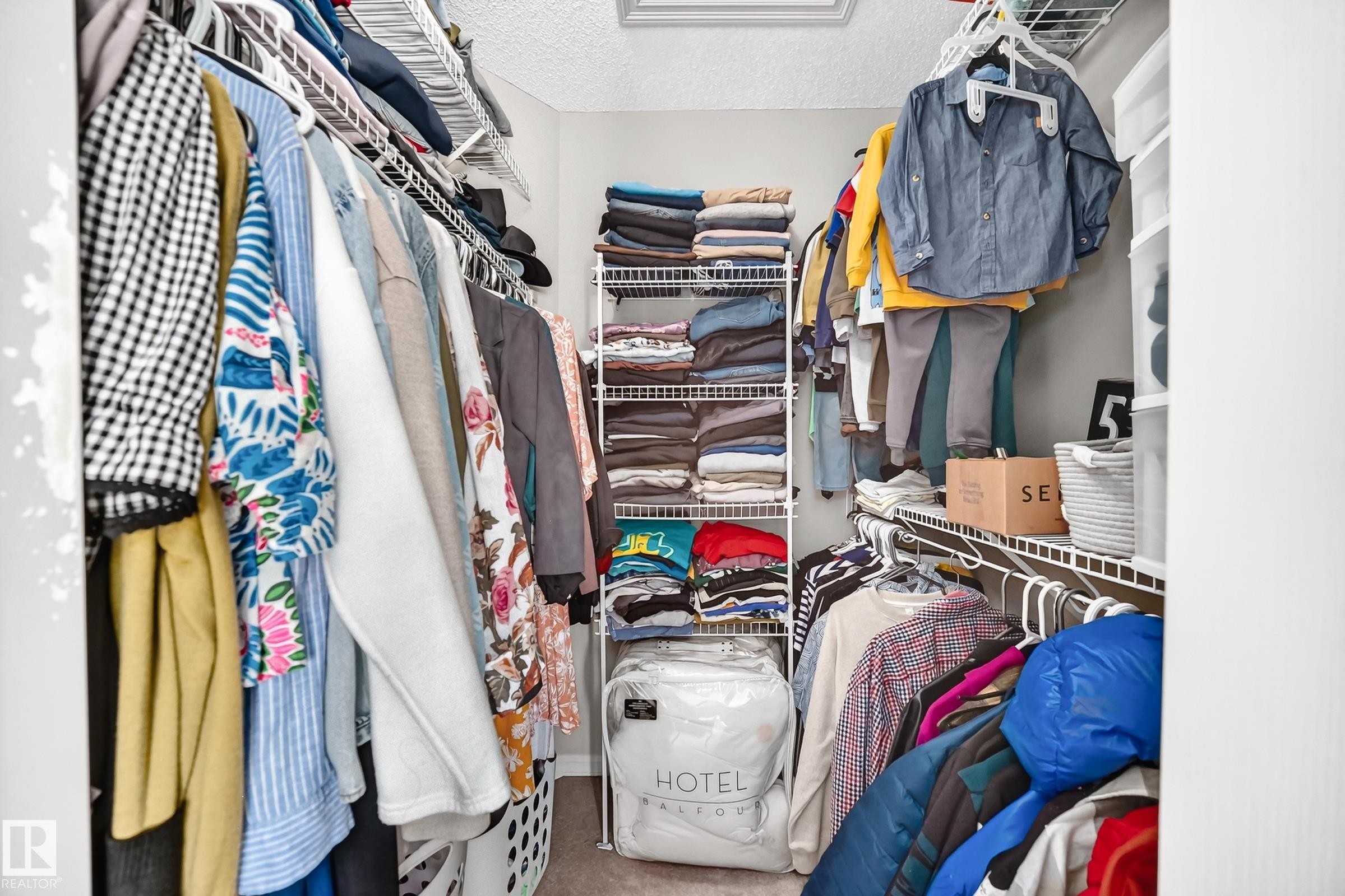 Walk-in closet featuring wire shelving, multiple hanging rods, and a standalone wire shelving unit - 3224 26 Street, Edmonton, AB