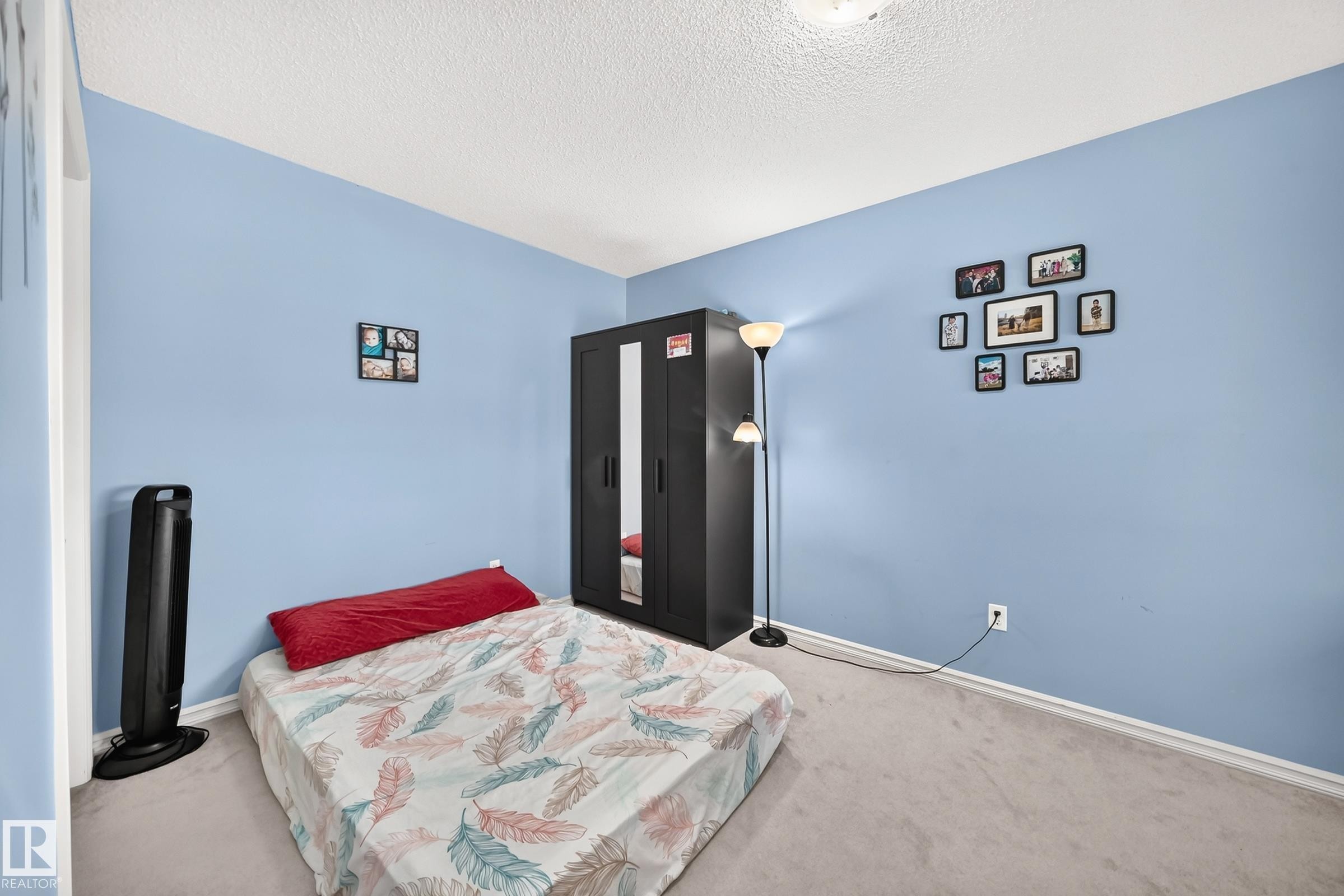 Bedroom featuring light blue walls, a textured ceiling, neutral carpet flooring, and white baseboards - 3224 26 Street, Edmonton, AB
