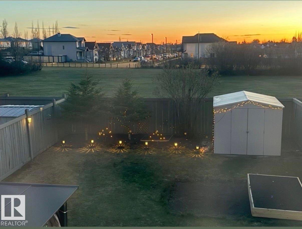 Expansive backyard featuring a manicured lawn, established trees, and a white storage shed - 3224 26 Street, Edmonton, AB