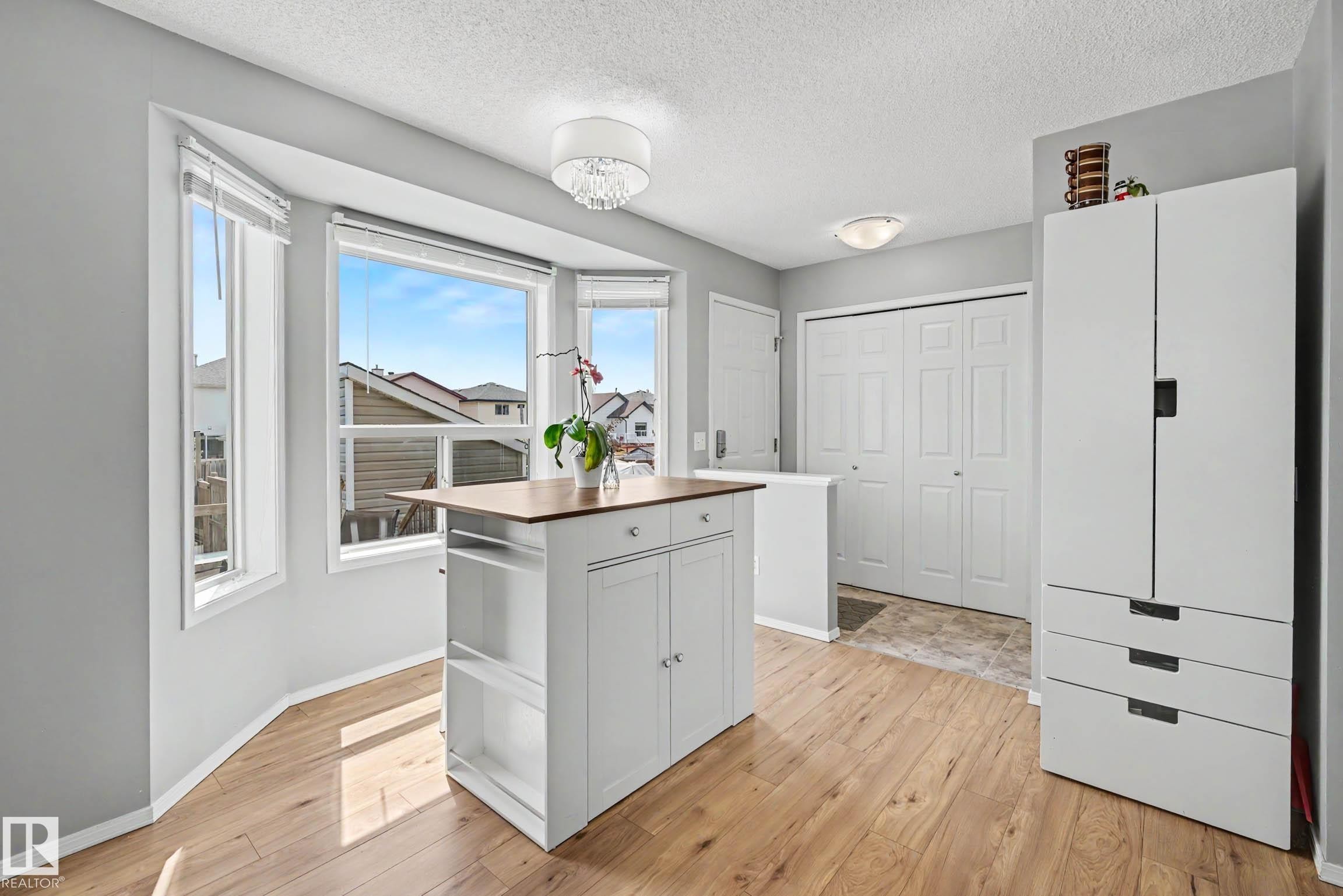 Kitchen area featuring light wood-finish flooring, a central island with a wood-finish countertop, and a bay window configuration - 2123 36 Avenue, Edmonton, AB - Indoor Photo Showing Other Room