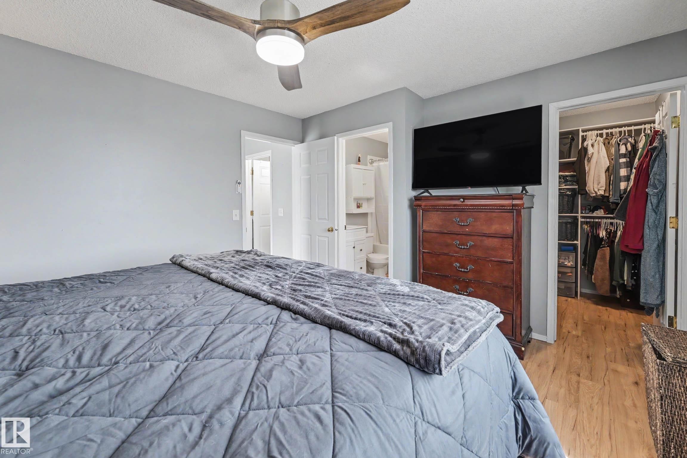 Bedroom featuring a contemporary ceiling fan with wood-finish blades, light gray wall paint, and wood-finish flooring in the open closet - 2123 36 Avenue, Edmonton, AB - Indoor Photo Showing Bedroom