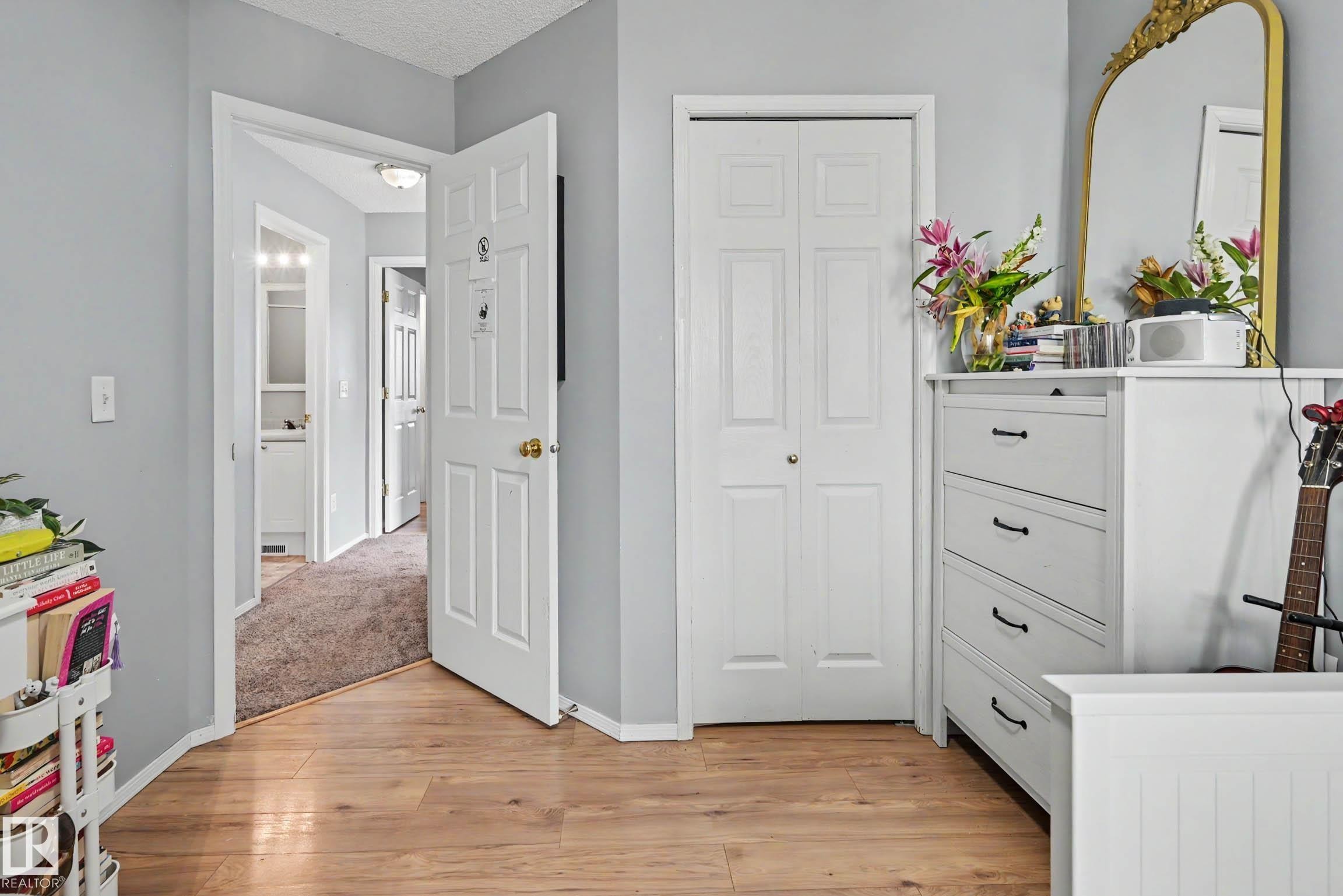 Wood-finish flooring throughout, featuring a white bi-fold closet door and a paneled entry door - 2123 36 Avenue, Edmonton, AB - Indoor Photo Showing Other Room