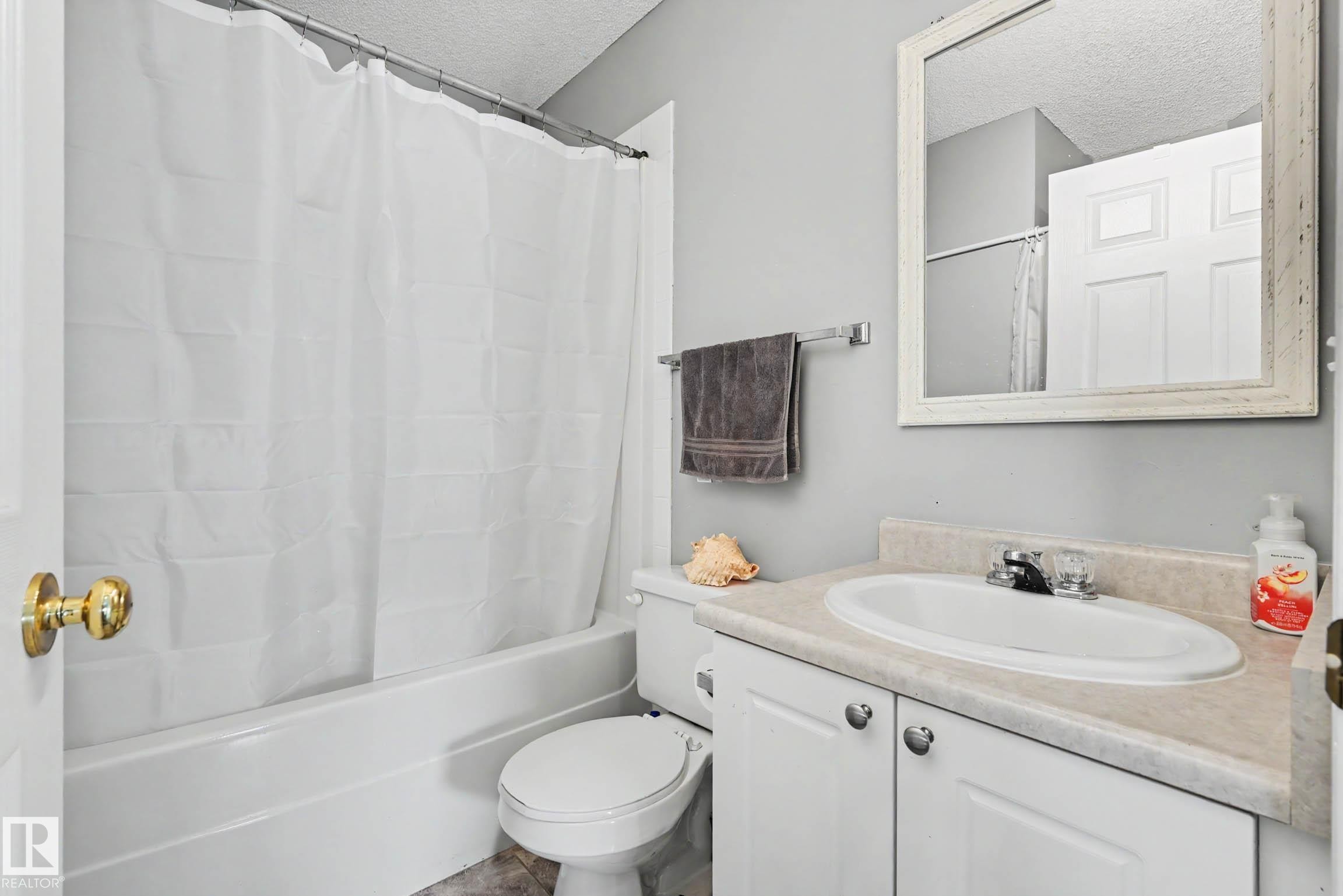 Bathroom featuring a white porcelain tub, toilet, and a vanity with an integrated sink - 2123 36 Avenue, Edmonton, AB - Indoor Photo Showing Bathroom