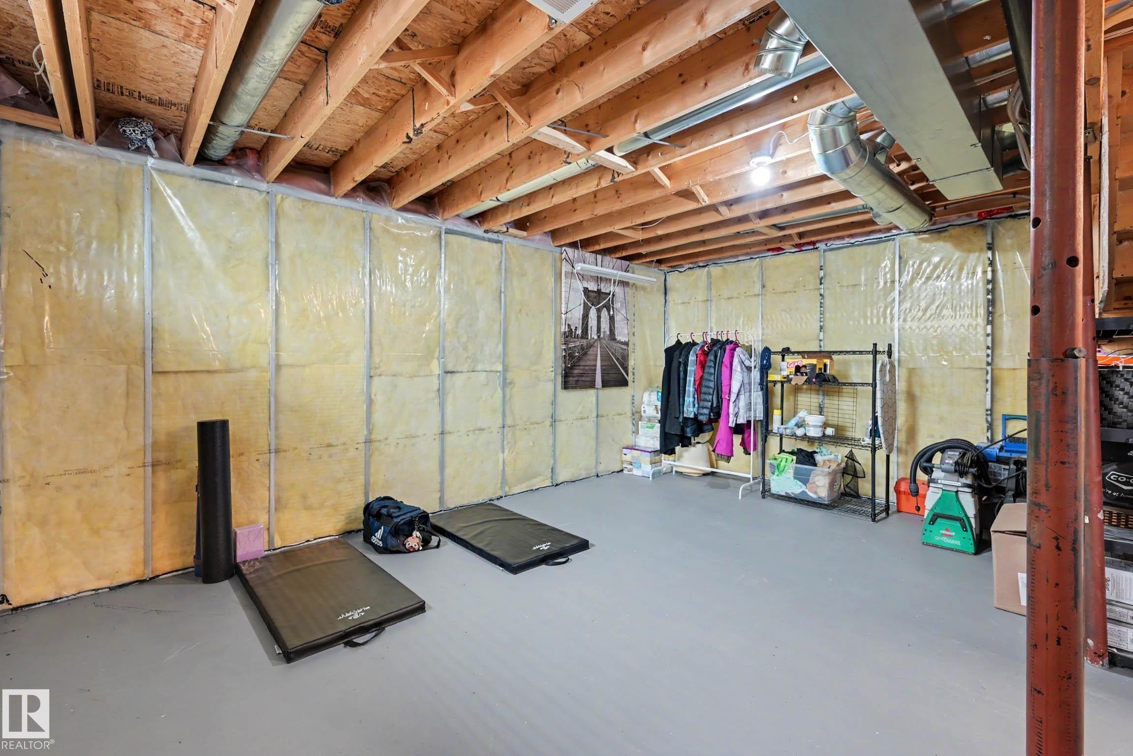 Unfinished basement area featuring exposed ceiling joists and ductwork, insulated wall panels, and a painted concrete floor - 2123 36 Avenue, Edmonton, AB - Indoor Photo Showing Basement