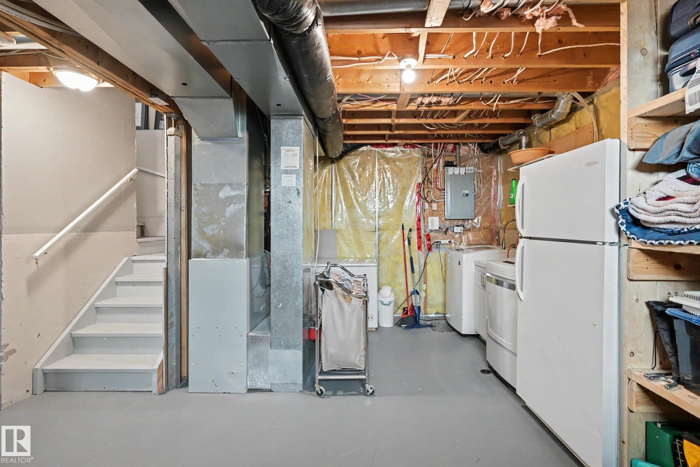 Utility area featuring exposed joist ceiling, painted concrete flooring, and a dedicated laundry space with a washer and dryer - 2123 36 Avenue, Edmonton, AB - Indoor Photo Showing Basement
