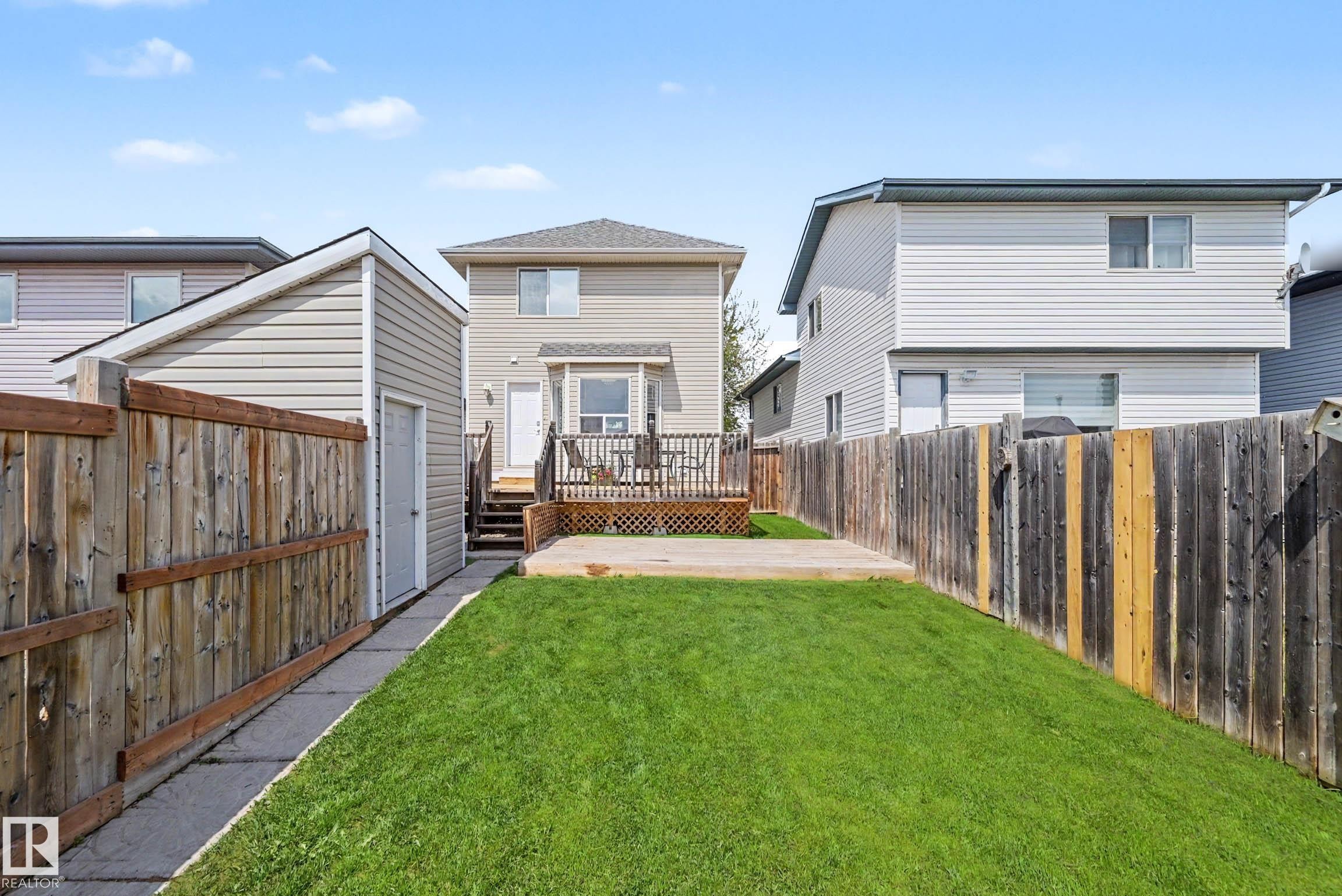 Expansive backyard featuring a manicured lawn, concrete patio, and a wood privacy fence - 2123 36 Avenue, Edmonton, AB - Outdoor With Deck Patio Veranda With Exterior