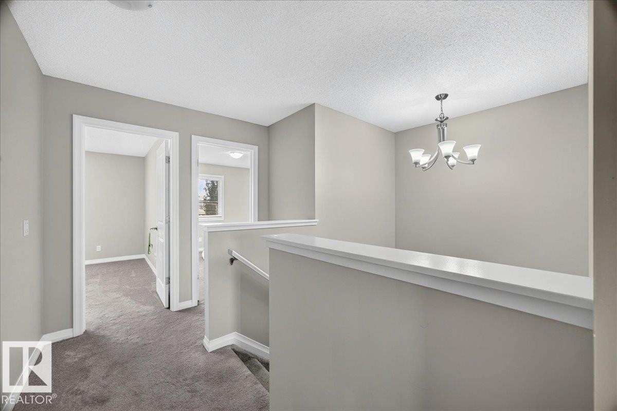 Upper-level hallway featuring a chandelier, light gray wall paint, and gray carpeting - 17203 71 Street, Edmonton, AB