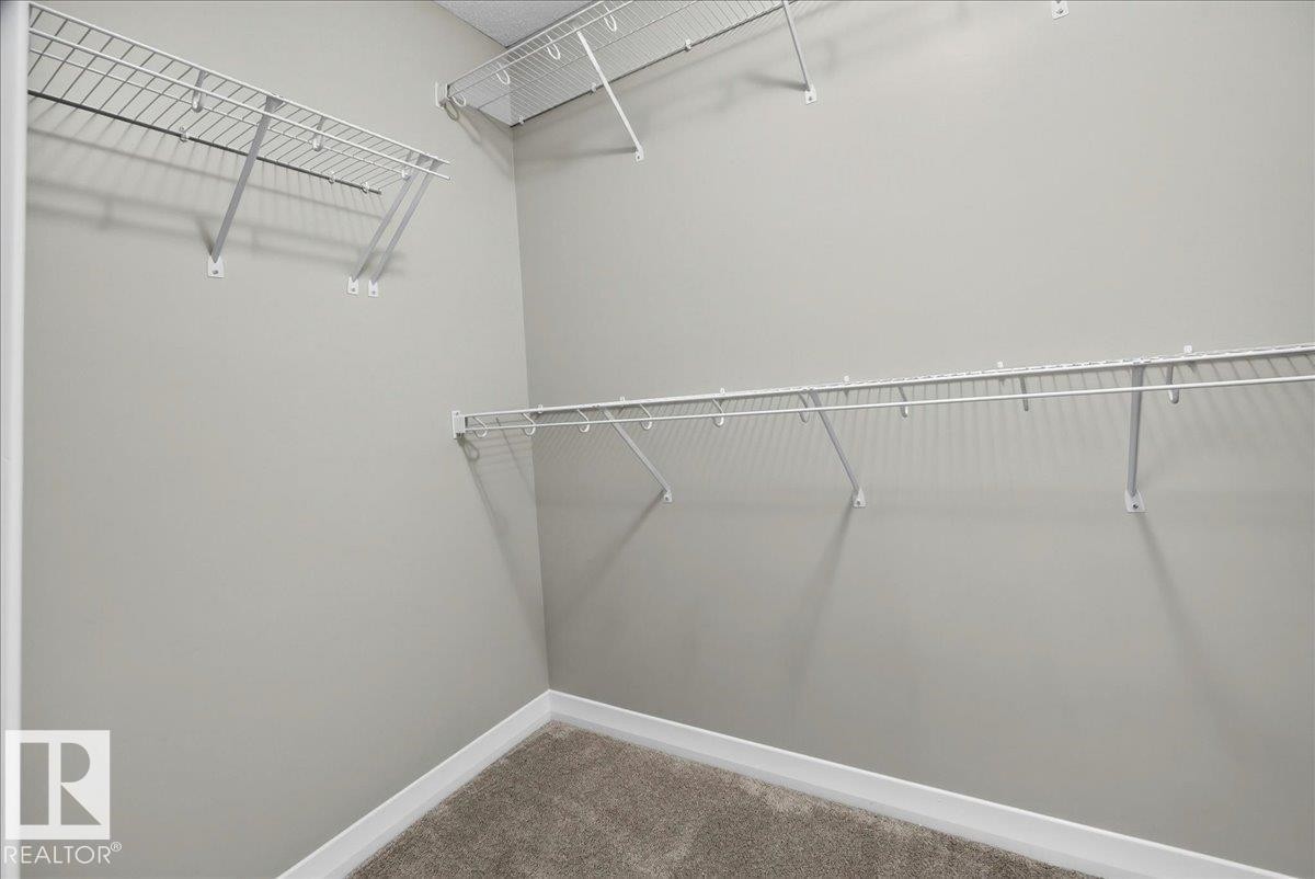 Walk-in closet with carpet flooring, light gray wall paint, white trim, and white wire shelving - 17203 71 Street, Edmonton, AB