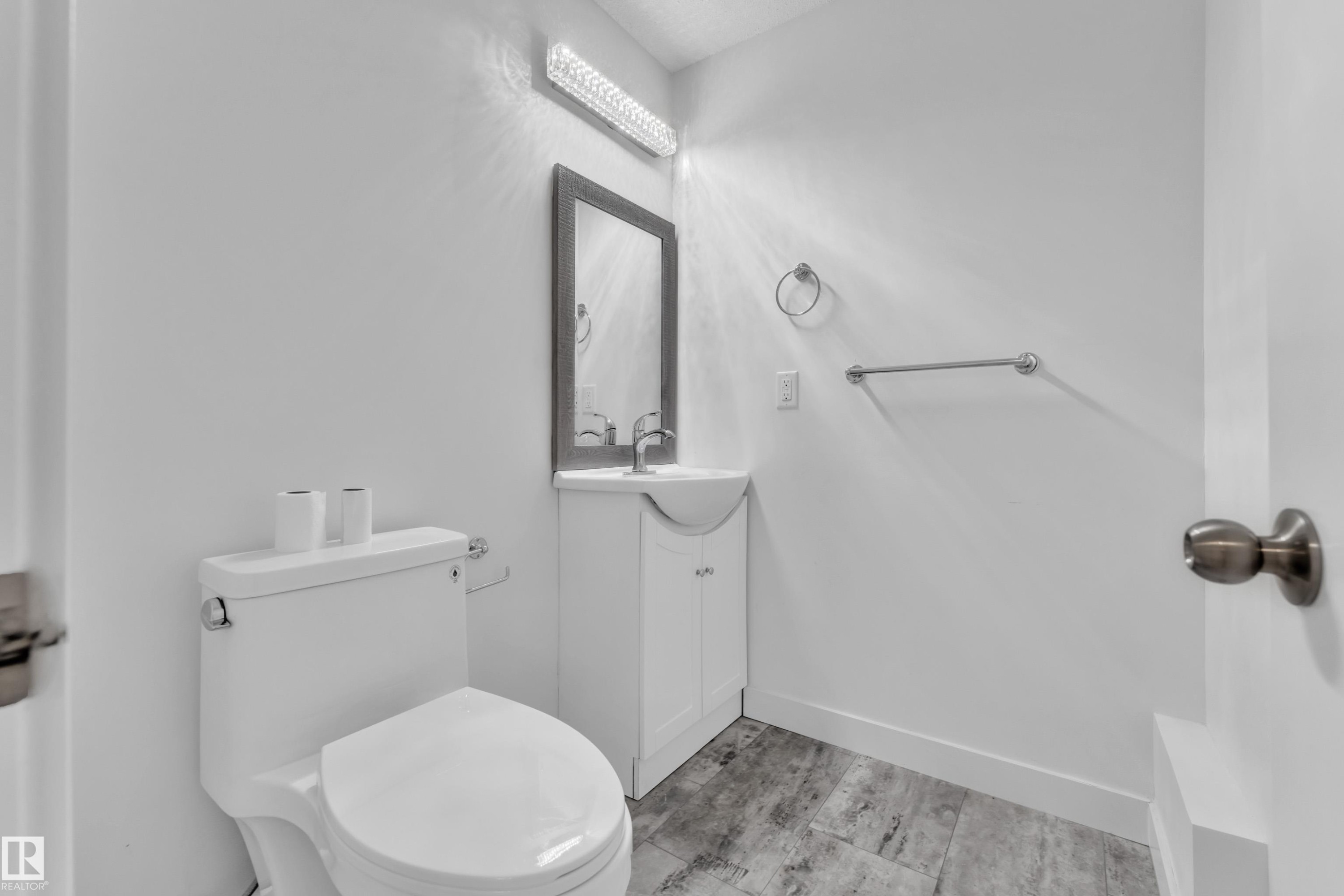 Bathroom featuring a contemporary vanity with an integrated sink, framed mirror, and wood-finish flooring - 144 Sunwapta Way, Edmonton, AB