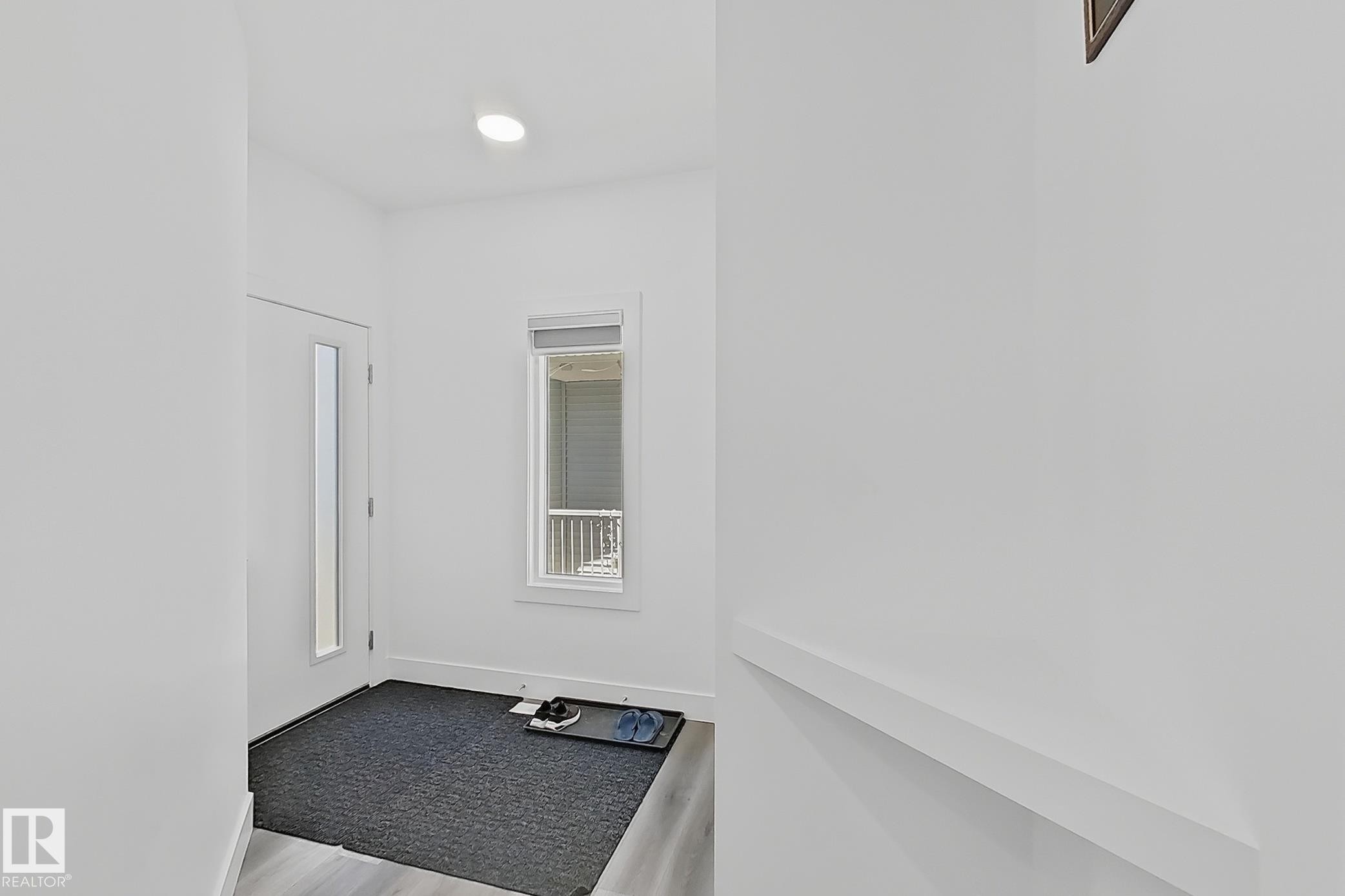 Entryway featuring contemporary light wood-finish flooring, a white paneled door with a vertical glass insert, and a recessed ceiling light - 415 42 Street, Edmonton, AB