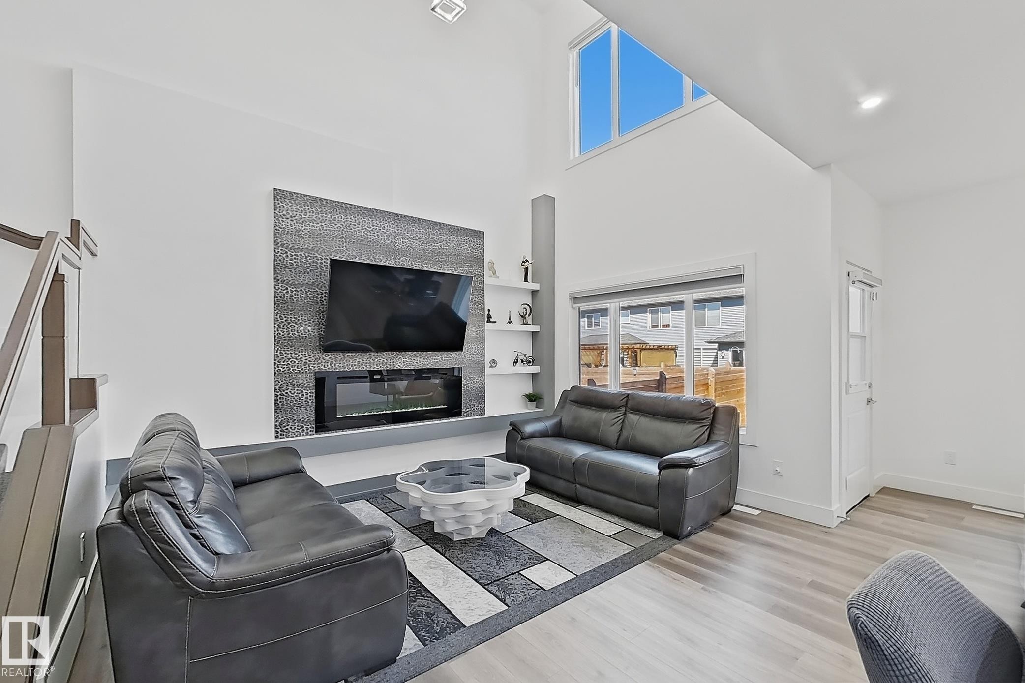 Spacious living area featuring a vaulted ceiling and an accent wall with an integrated electric fireplace - 415 42 Street, Edmonton, AB