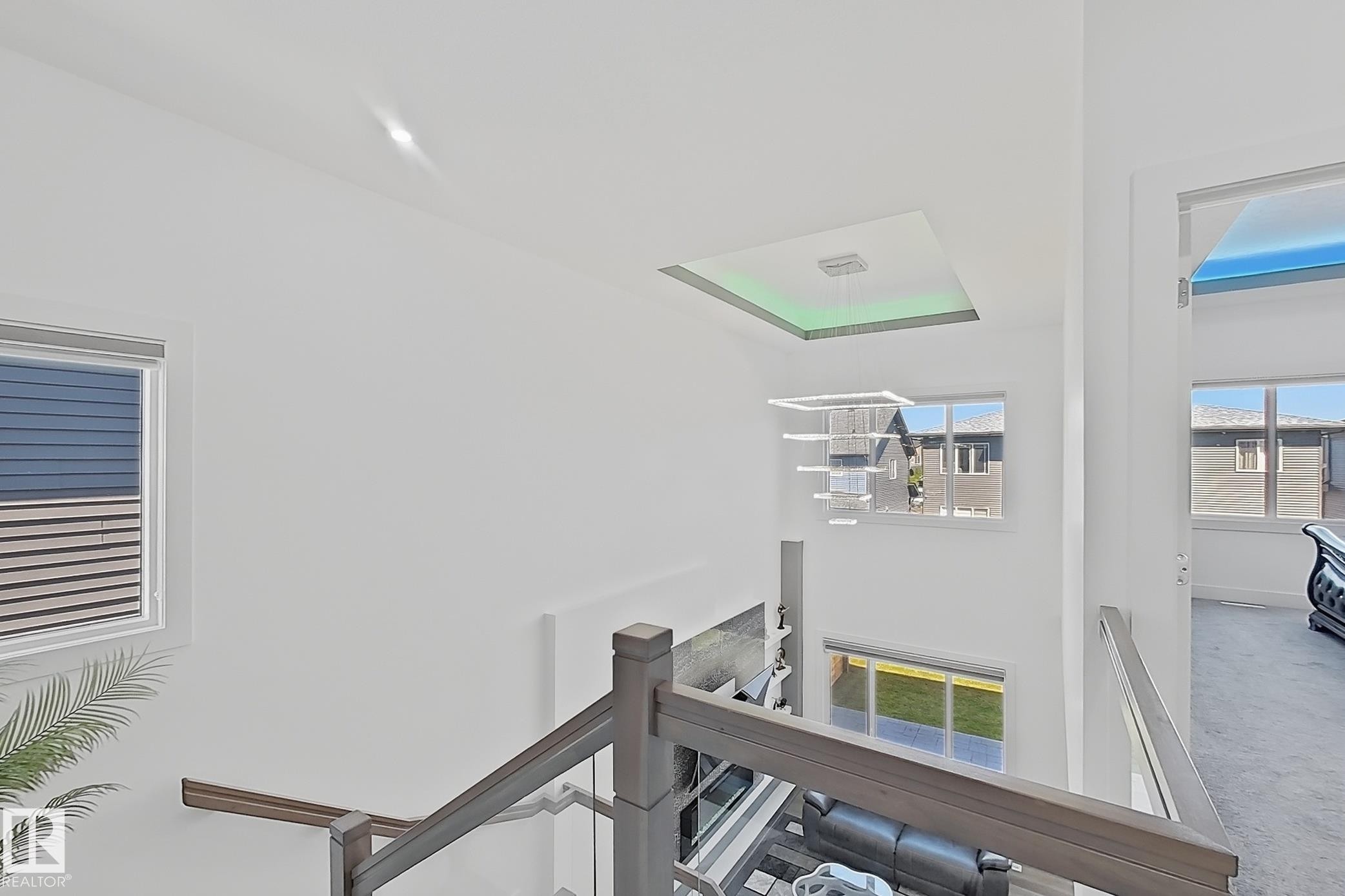 Upper-level landing featuring a wood-finish handrail with glass paneling, an overhead recessed light fixture, and white walls - 415 42 Street, Edmonton, AB