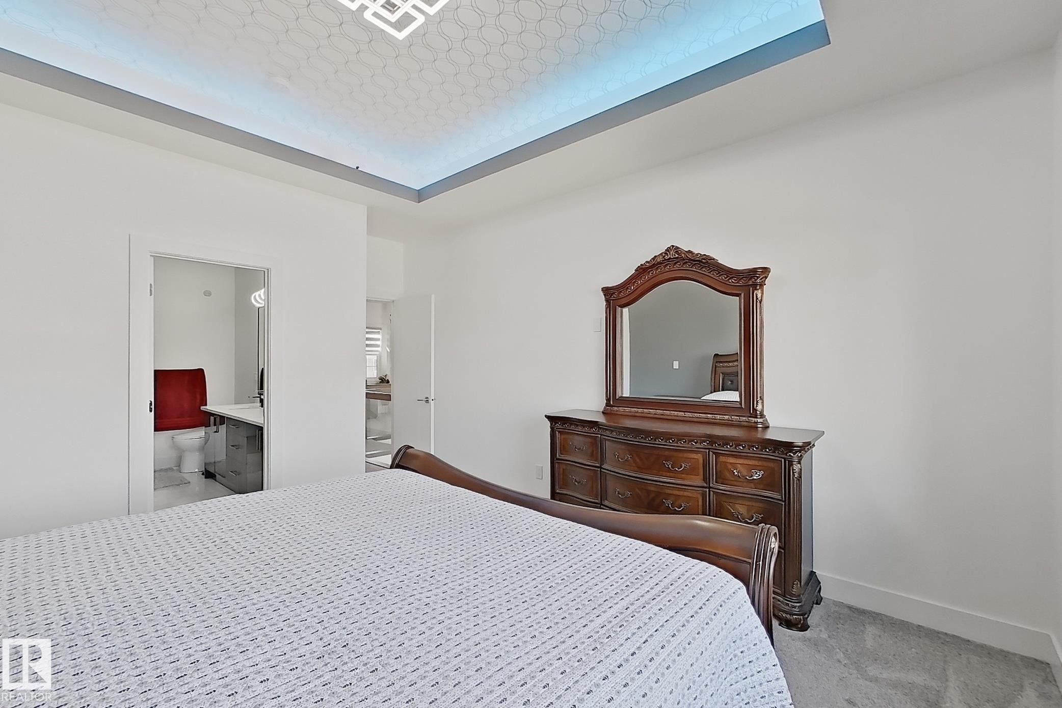 Spacious bedroom featuring light-toned carpet flooring and a tray ceiling with integrated lighting - 415 42 Street, Edmonton, AB