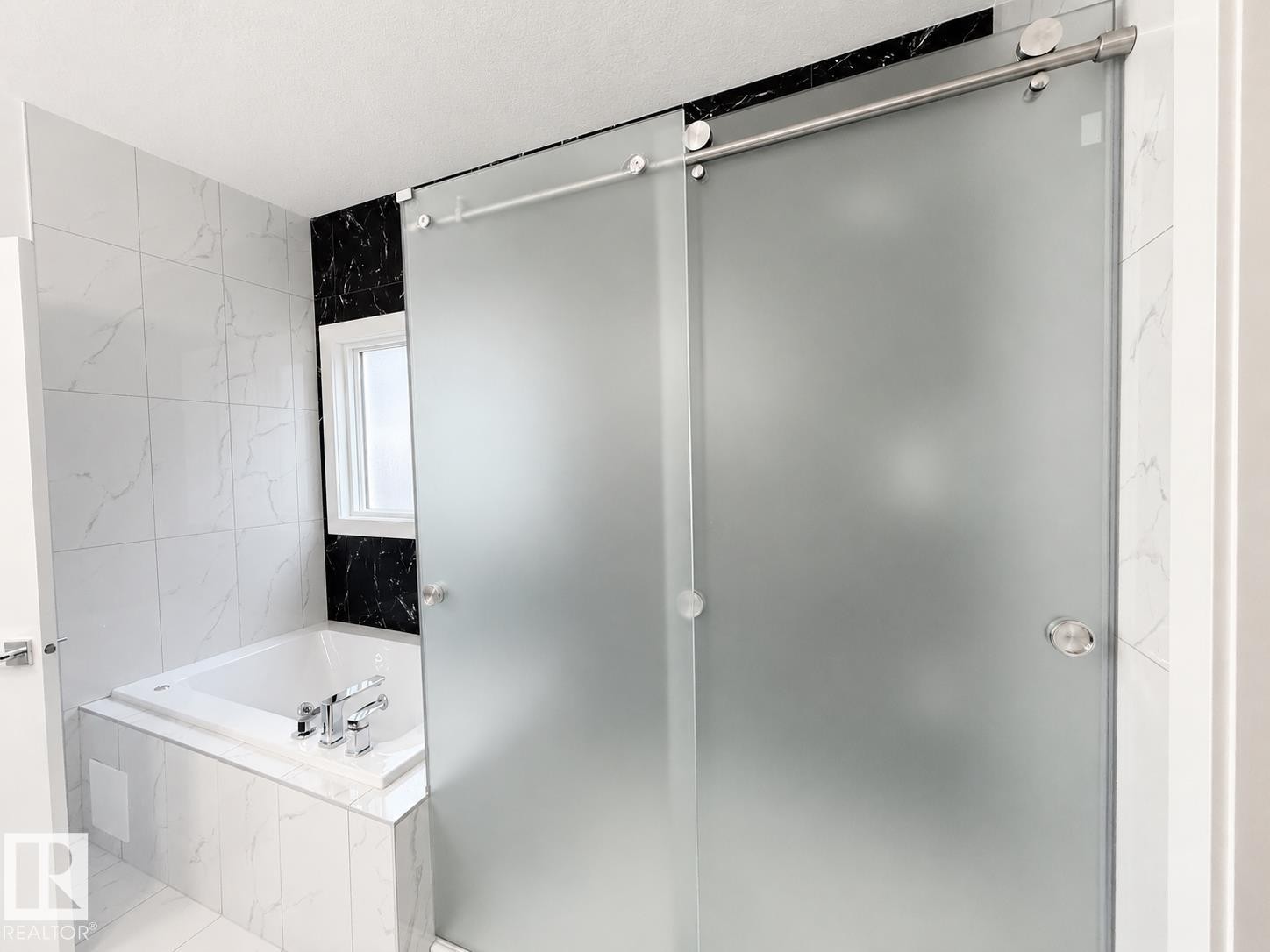 Frosted glass sliding shower door with stainless steel hardware, set against a backdrop of white and black veined tiling - 415 42 Street, Edmonton, AB