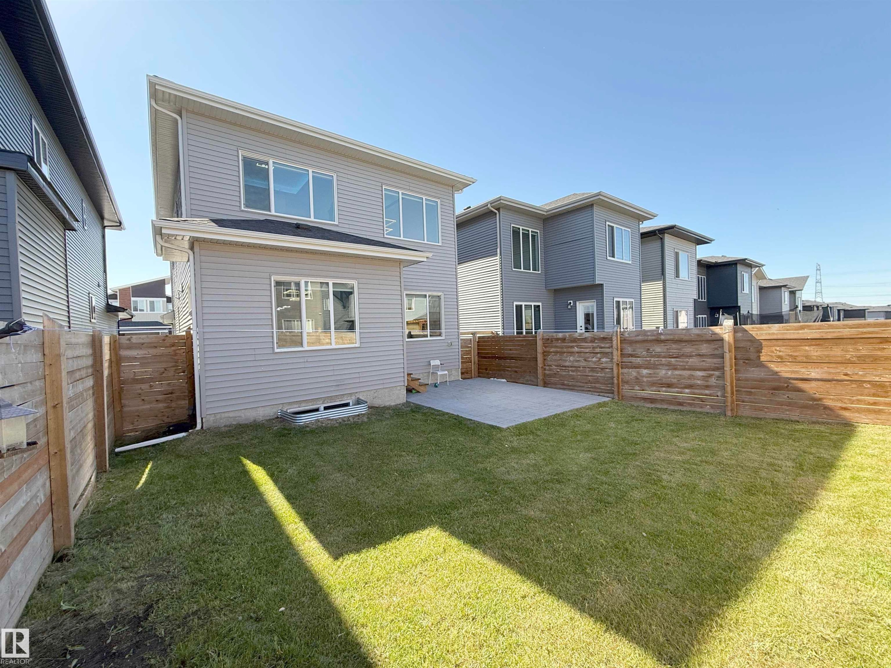 Expansive backyard featuring a lush lawn, a concrete patio, and privacy fencing - 415 42 Street, Edmonton, AB