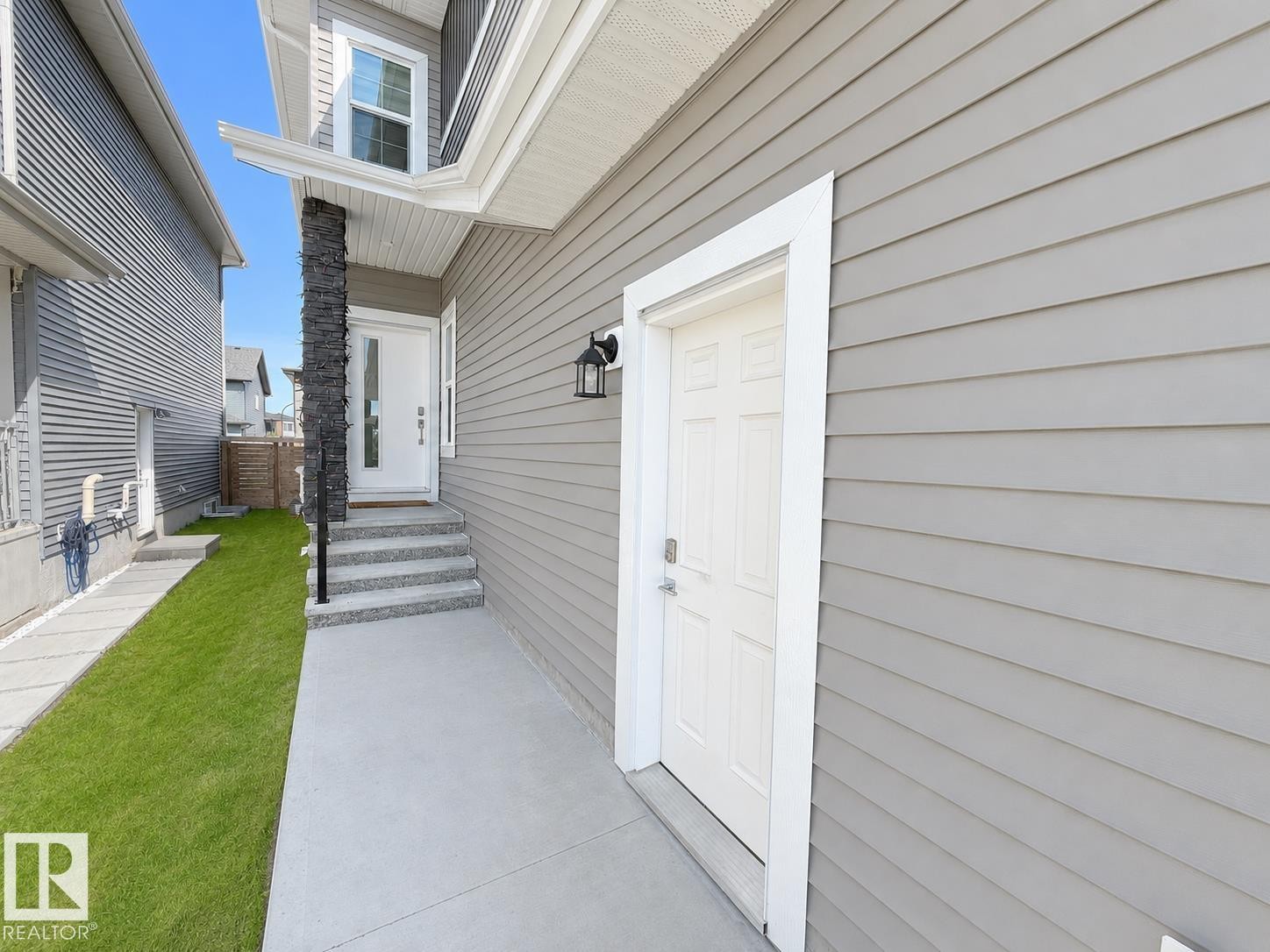 Exterior entry featuring light gray horizontal siding and a white paneled door - 415 42 Street, Edmonton, AB