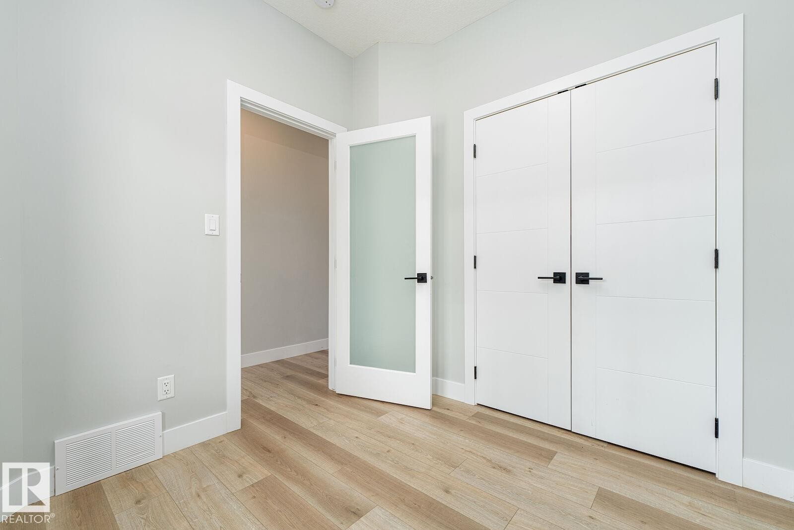 Light wood-finish flooring with white baseboards and neutral wall tones - 17320 9 Avenue, Edmonton, AB