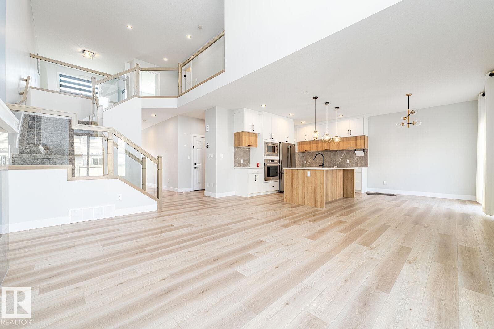 Spacious open-concept living area featuring light wood-finish flooring - 17320 9 Avenue, Edmonton, AB