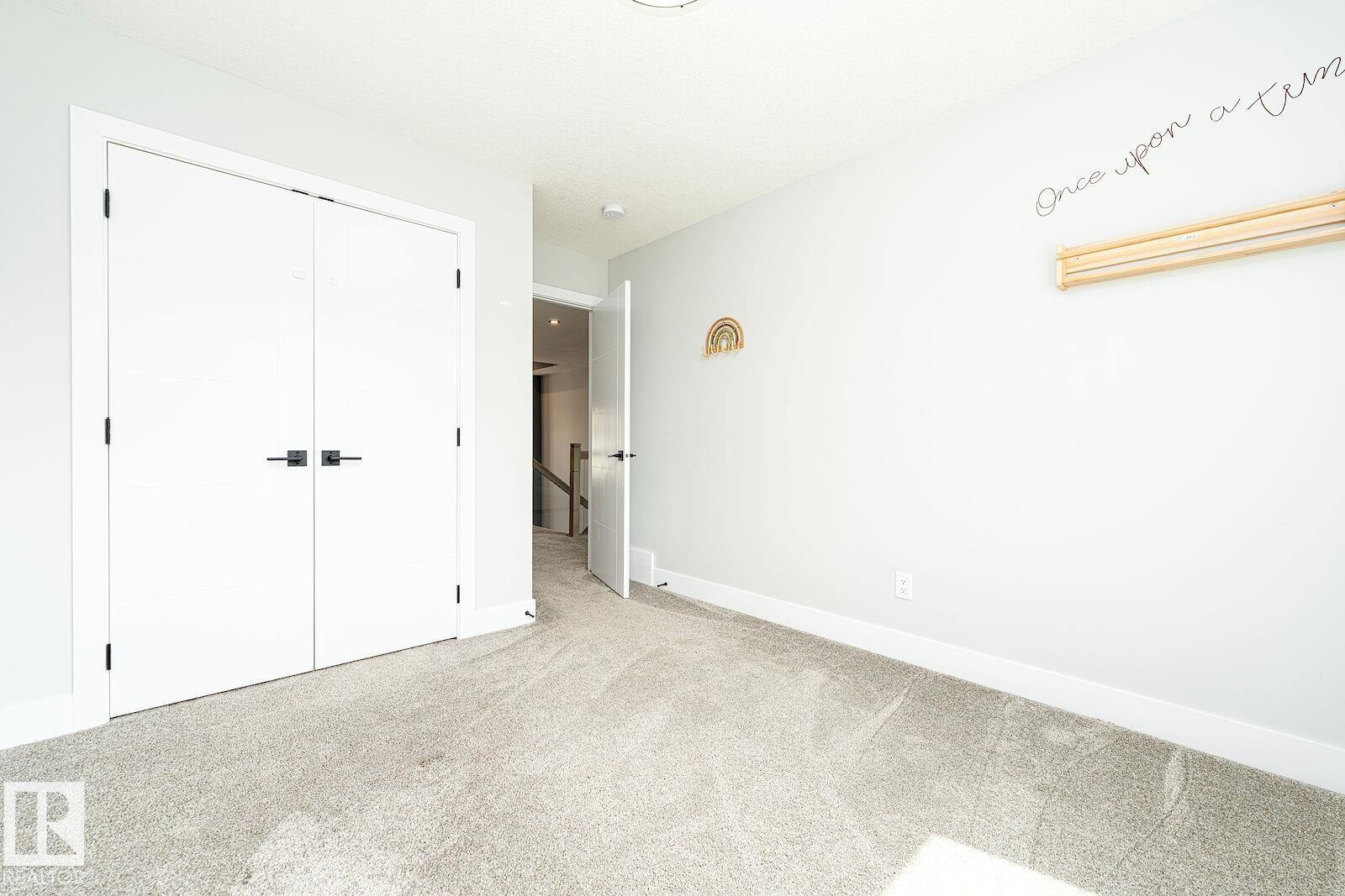 Room featuring light gray carpeting, white walls, and modern white doors with black hardware - 17320 9 Avenue, Edmonton, AB