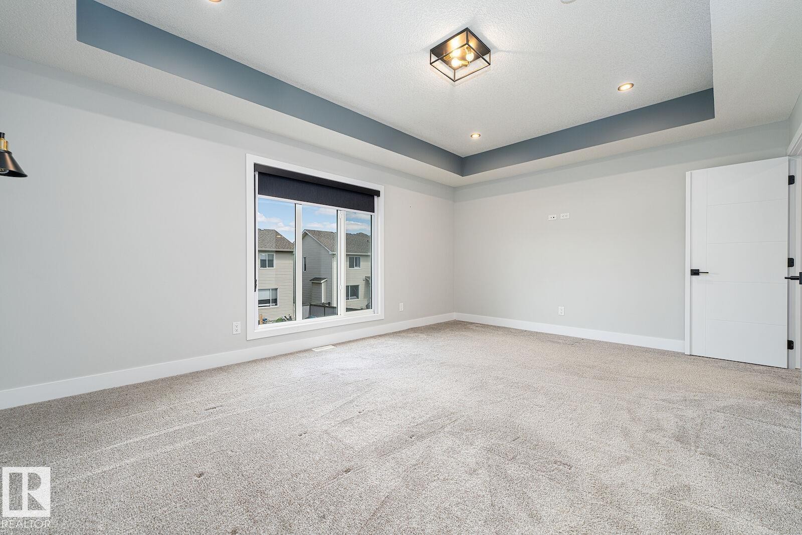 Spacious room featuring light gray carpeting and white baseboards - 17320 9 Avenue, Edmonton, AB