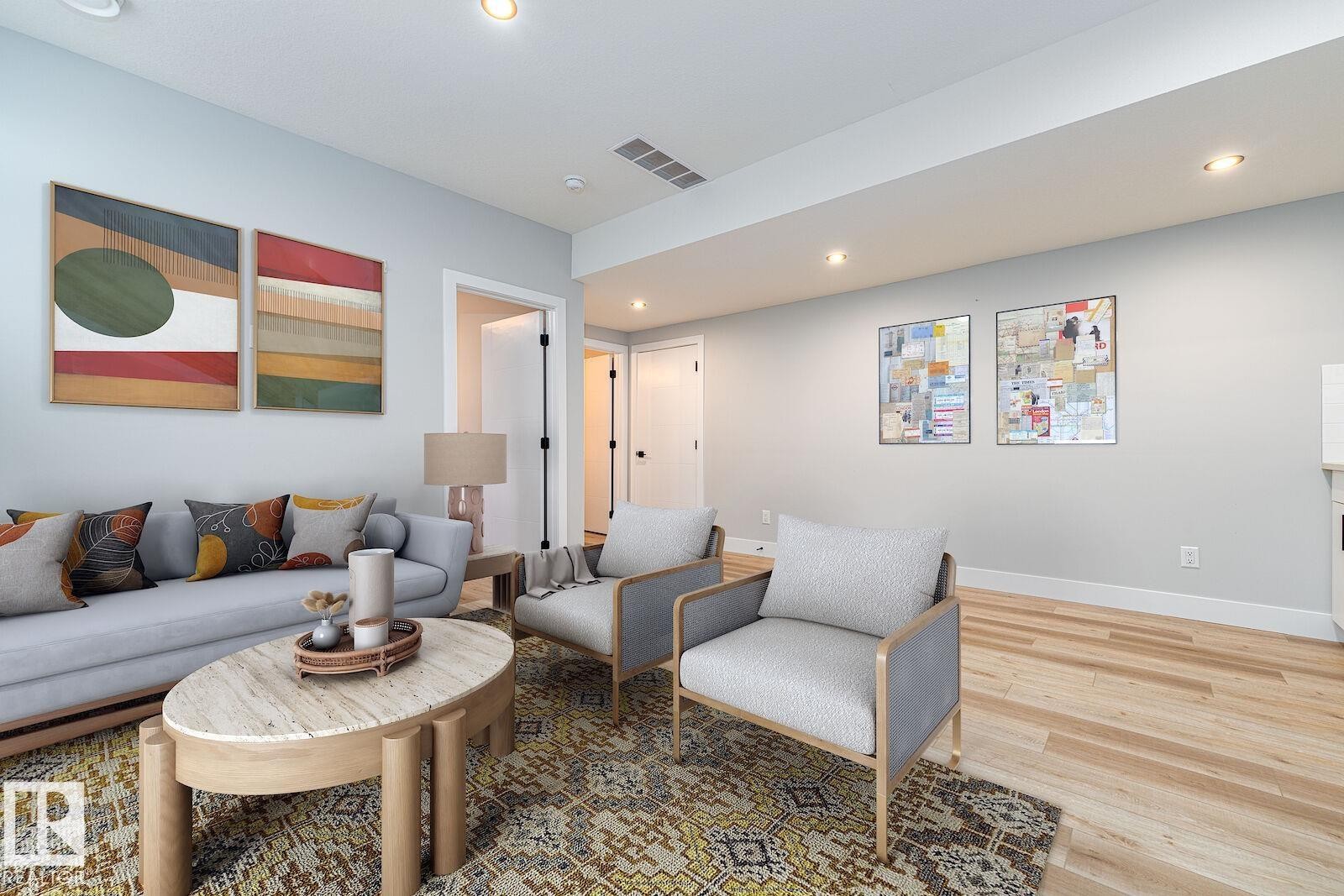 Spacious living area featuring light wood-finish flooring, recessed lighting, white baseboards, and light neutral wall tones - 17320 9 Avenue, Edmonton, AB