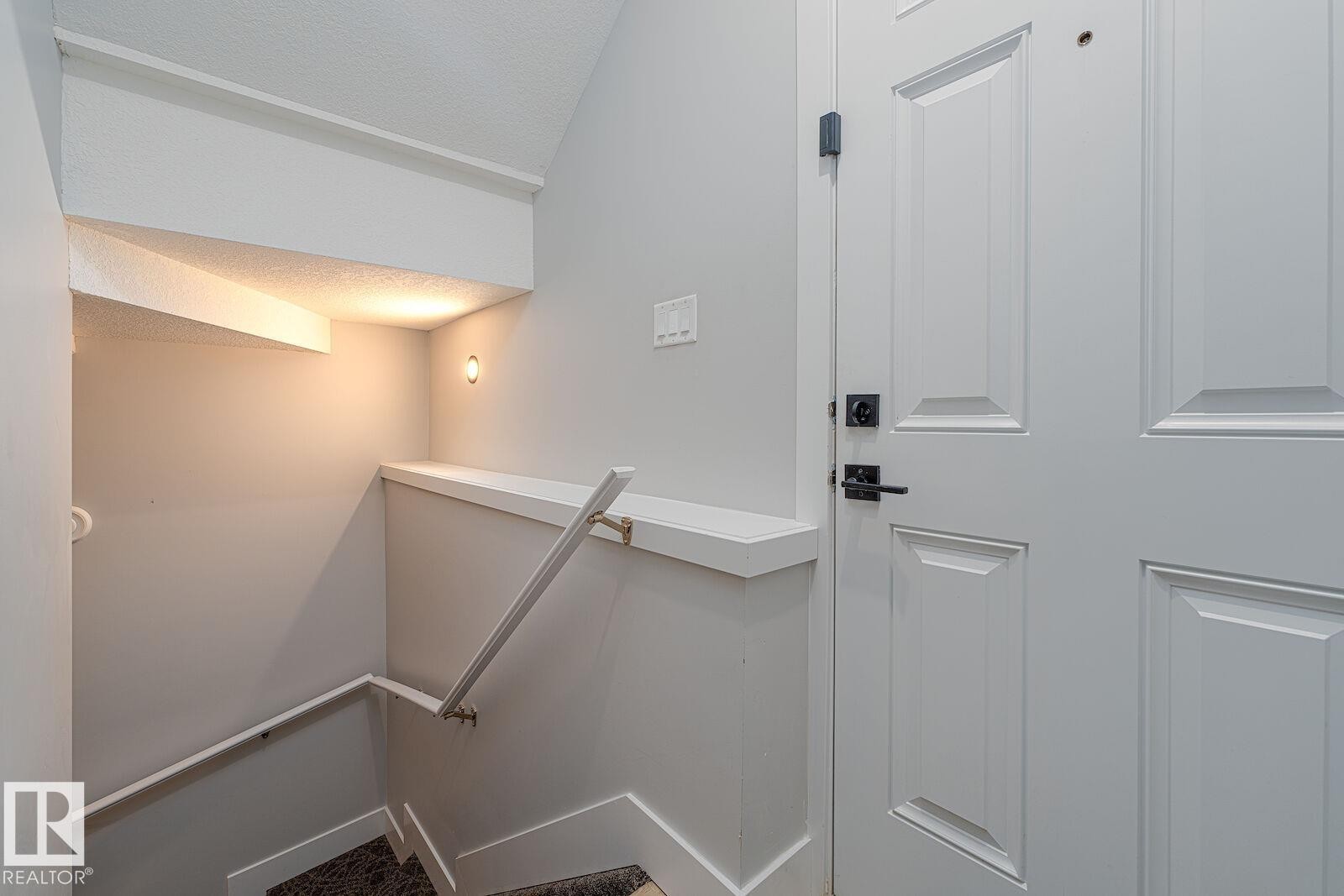 Paneled interior door with matte black hardware, featuring a built-in wall shelf - 17320 9 Avenue, Edmonton, AB