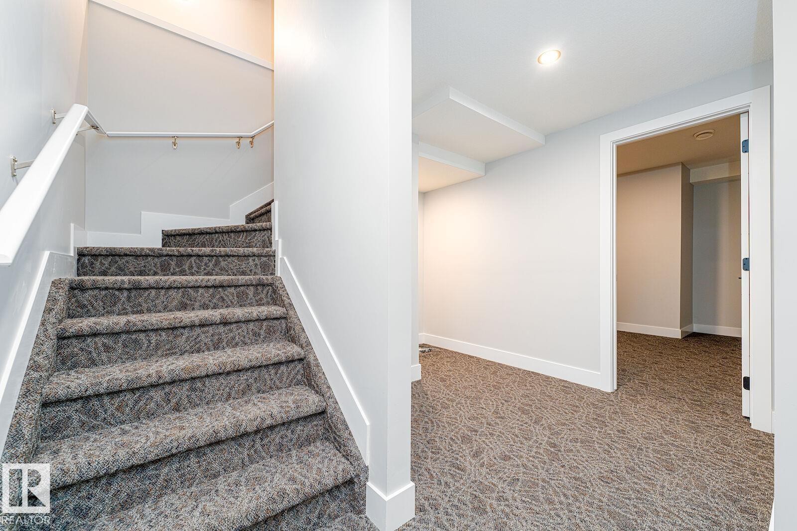 Staircase with patterned gray carpet, white risers, and a white handrail - 17320 9 Avenue, Edmonton, AB
