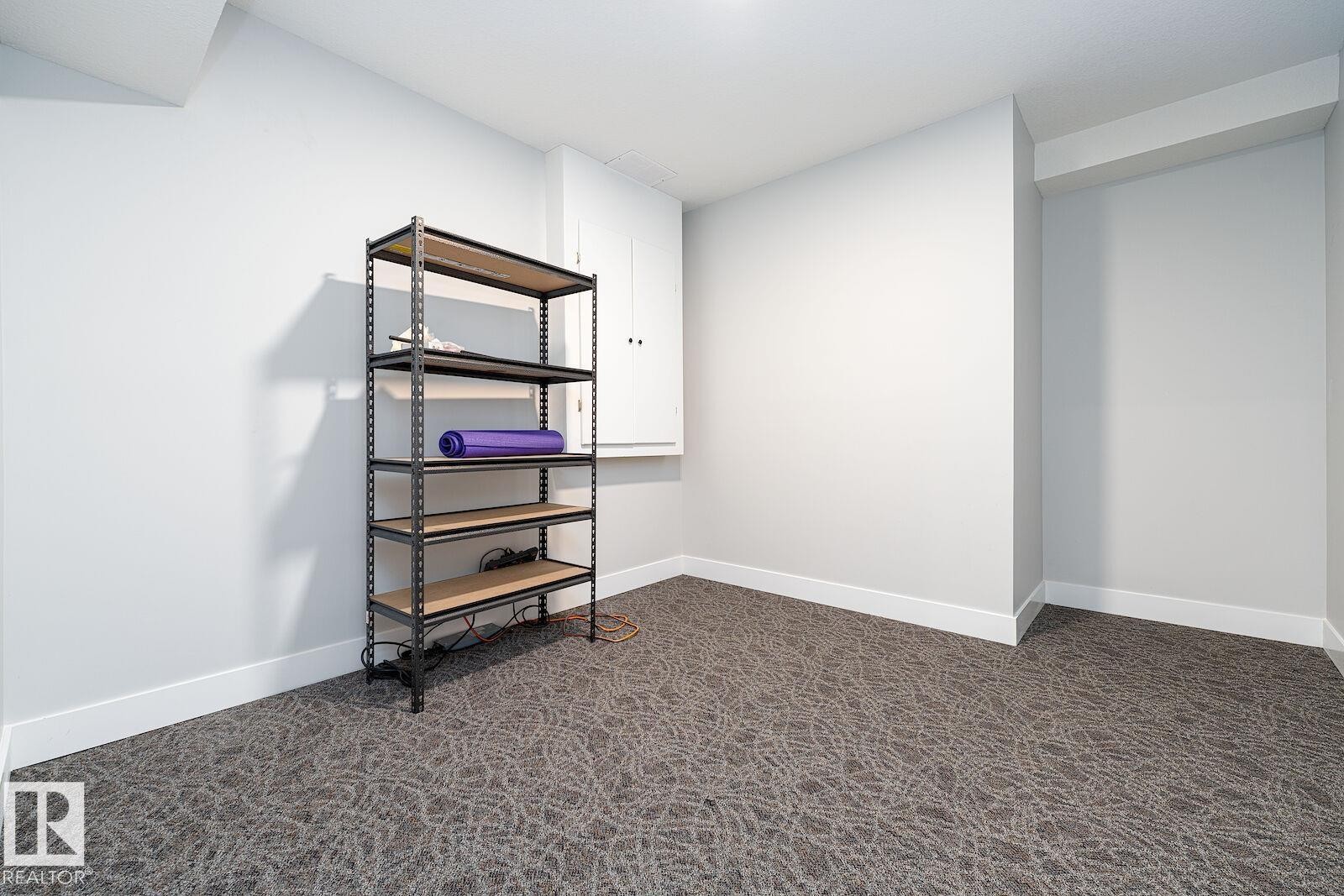 Recessed space featuring neutral-toned walls, patterned carpeting, and white baseboards - 17320 9 Avenue, Edmonton, AB