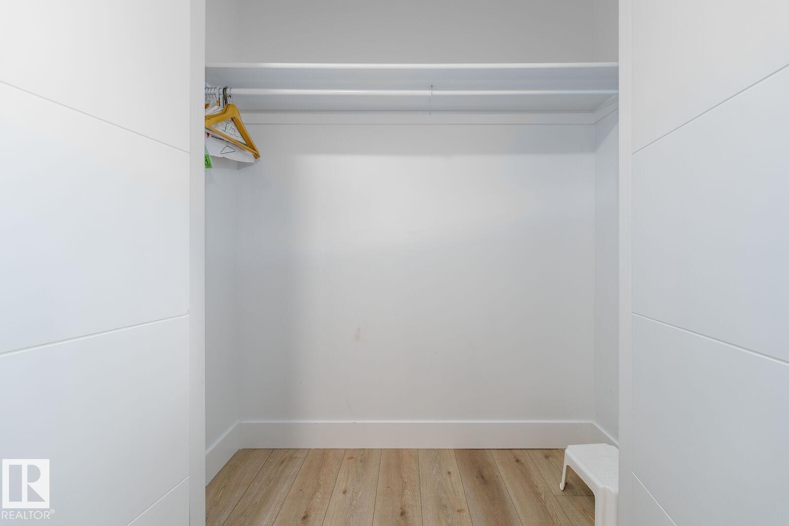 Interior closet featuring light wood-finish flooring, white walls, and a white clothes hanging rod - 17320 9 Avenue, Edmonton, AB