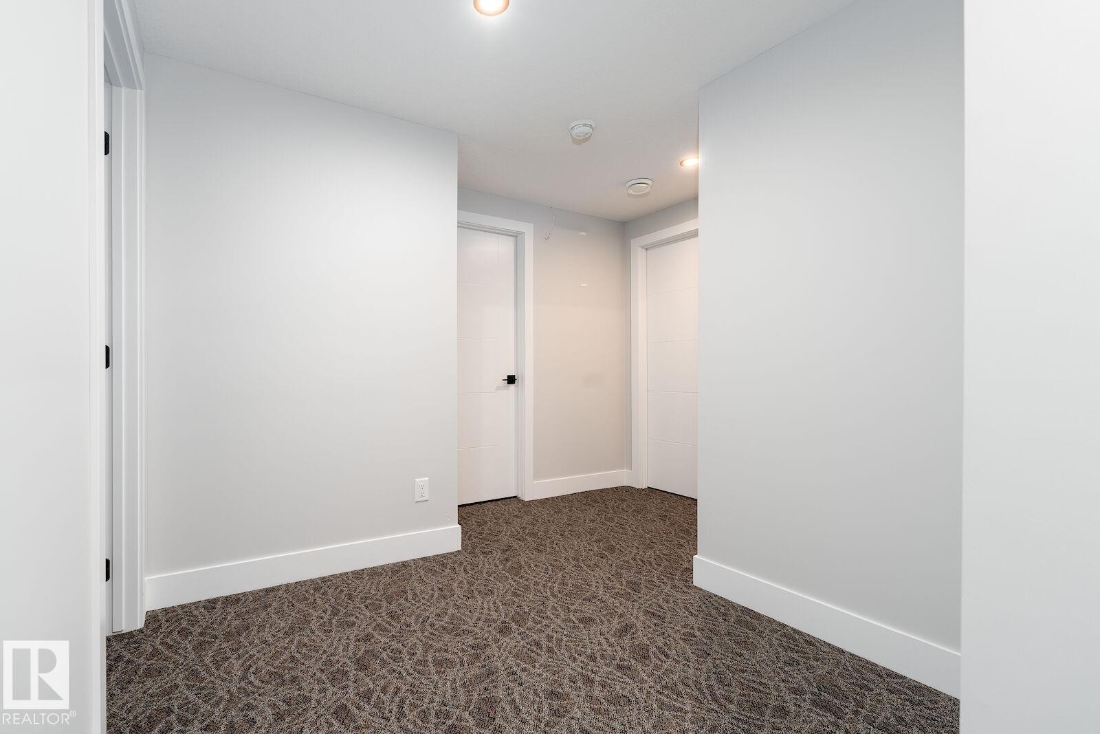 Hallway featuring patterned carpet, white walls, and recessed lighting - 17320 9 Avenue, Edmonton, AB