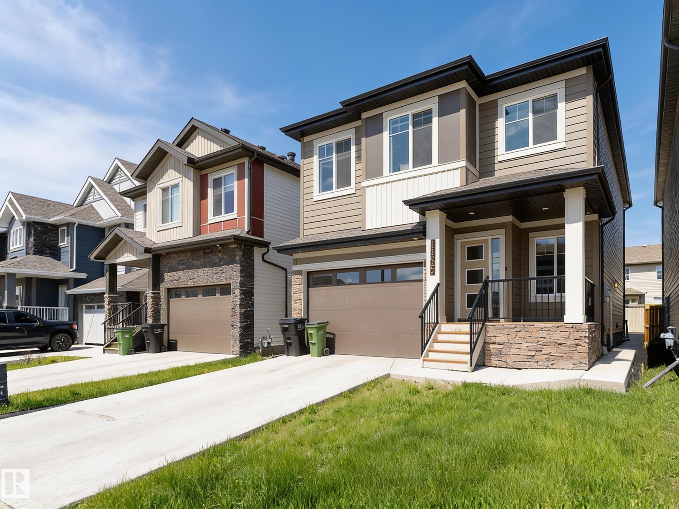 Contemporary two-story residence featuring a covered front porch with stone accents, a single-car garage, and a concrete driveway - 17320 9 Avenue, Edmonton, AB