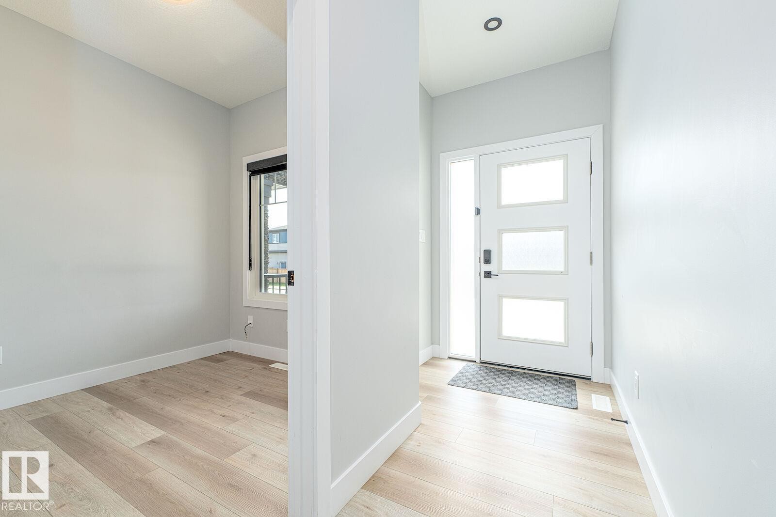 Entryway featuring a modern front door with three frosted glass panels and a full-length side light - 17320 9 Avenue, Edmonton, AB