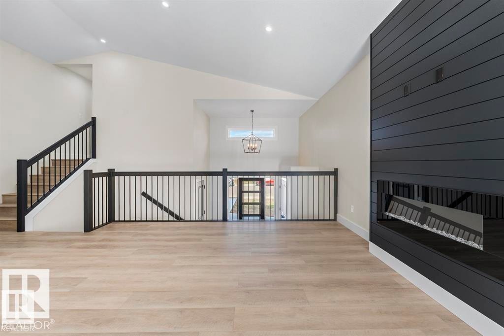 Spacious interior featuring wood-finish flooring, a contemporary fireplace with dark shiplap surround, and an open-concept layout with vaulted ceilings - 301 Fundy Way, Cold Lake, AB - Indoor Photo Showing Other Room