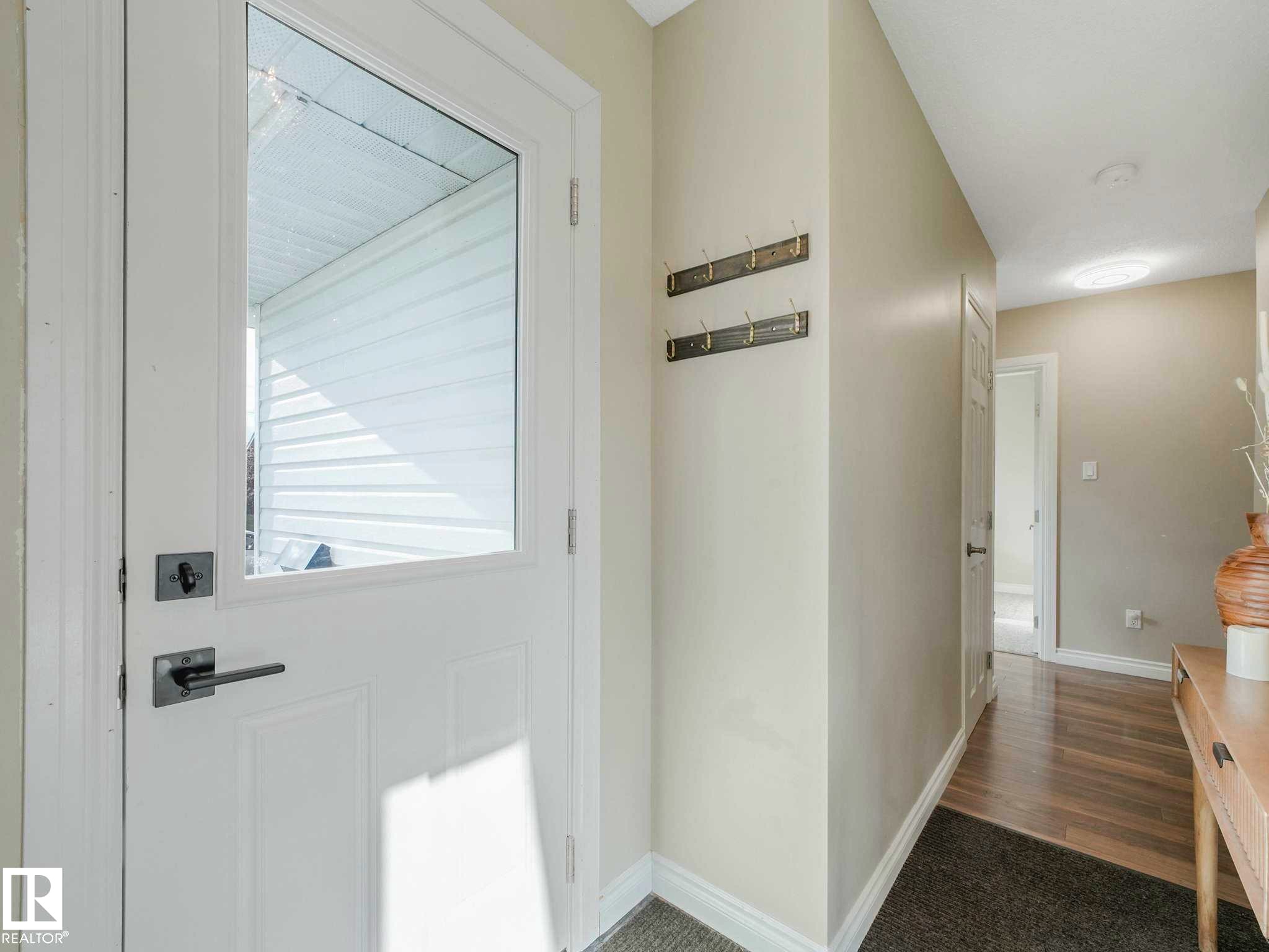 Entryway featuring a white door with a clear glass insert, contemporary brushed nickel hardware, and wood-finish flooring - 9207 169 Street, Edmonton, AB - Indoor Photo Showing Other Room
