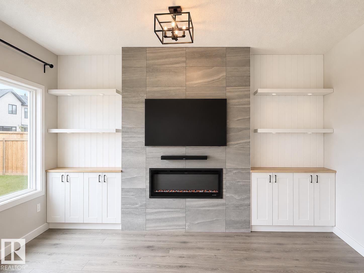 Living area featuring a floor-to-ceiling fireplace with stone-look tile surround and an integrated electric fireplace - 3234 Chernowski Way, Edmonton, AB