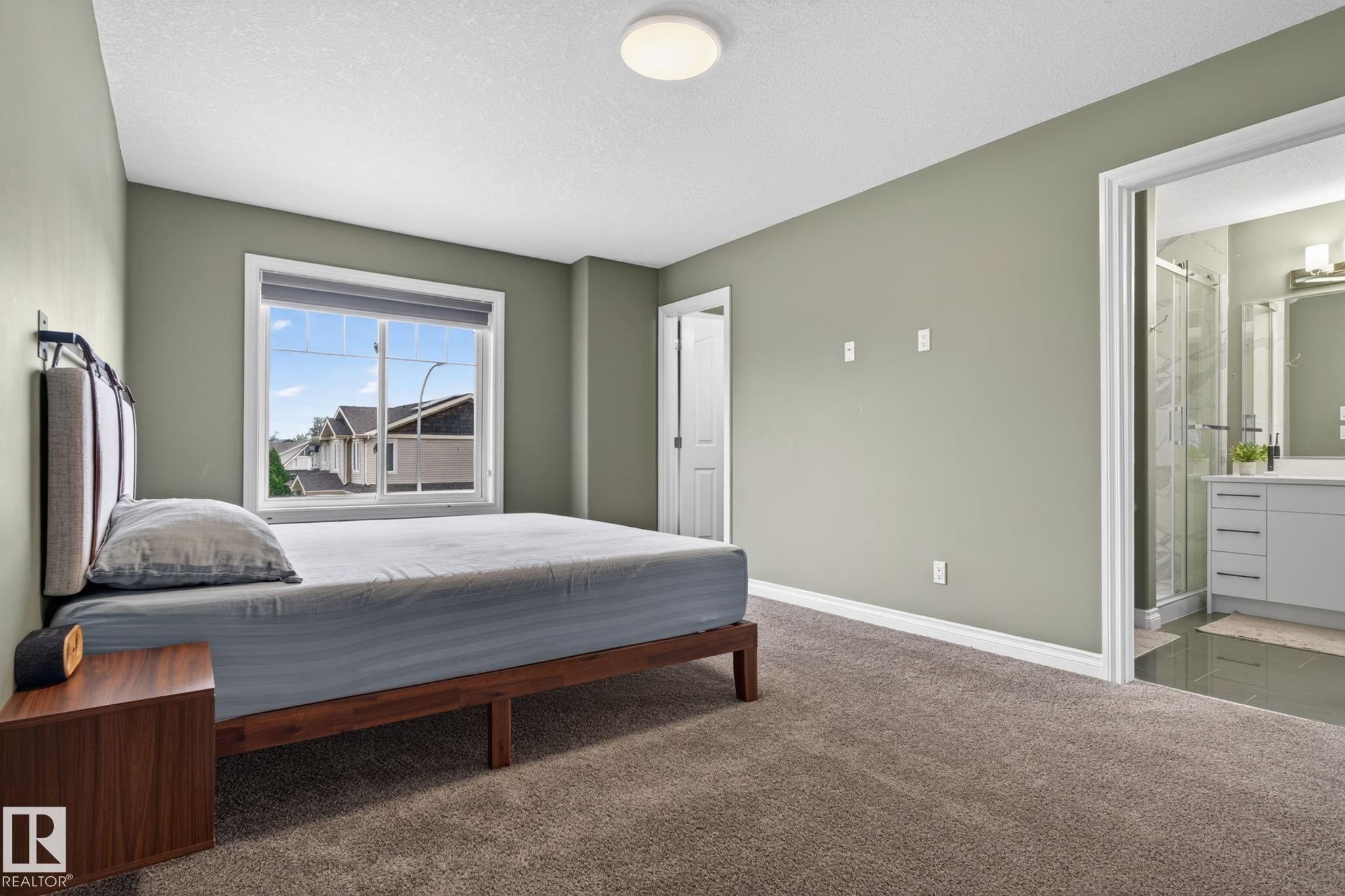 Bedroom featuring soft green walls, plush carpet flooring, and a large window with white trim - 9628 221 Street, Edmonton, AB