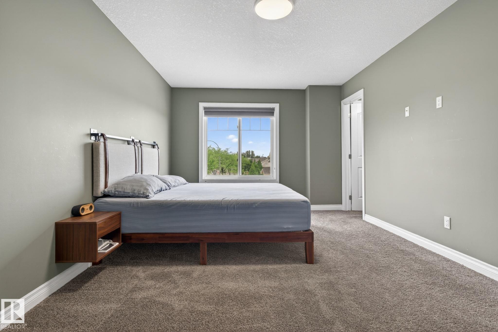 Bedroom featuring neutral-toned carpeting, a window with exterior views, and light green walls - 9628 221 Street, Edmonton, AB