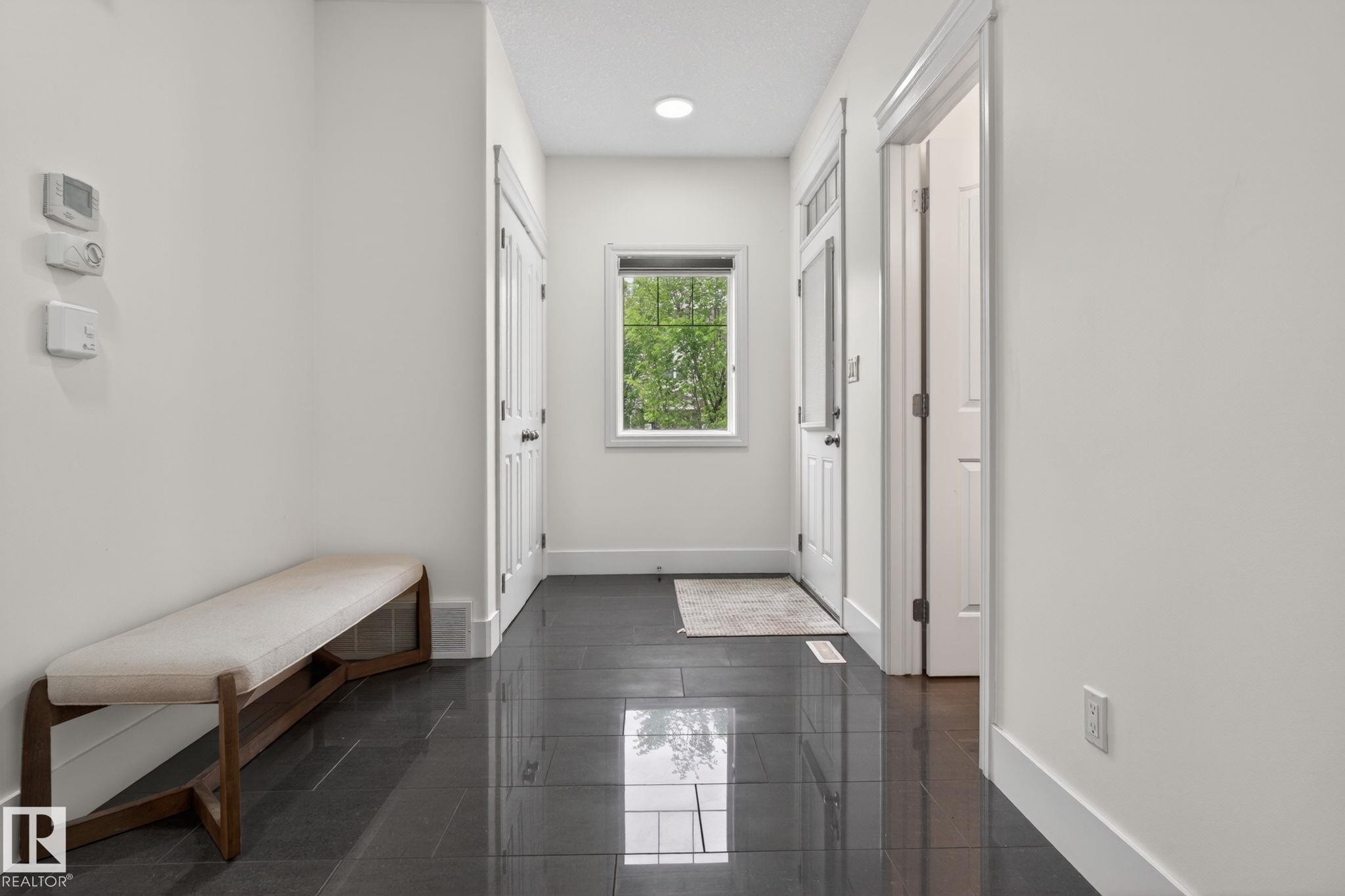 Entryway featuring dark tile flooring, white baseboards, and a window with natural light - 9628 221 Street, Edmonton, AB
